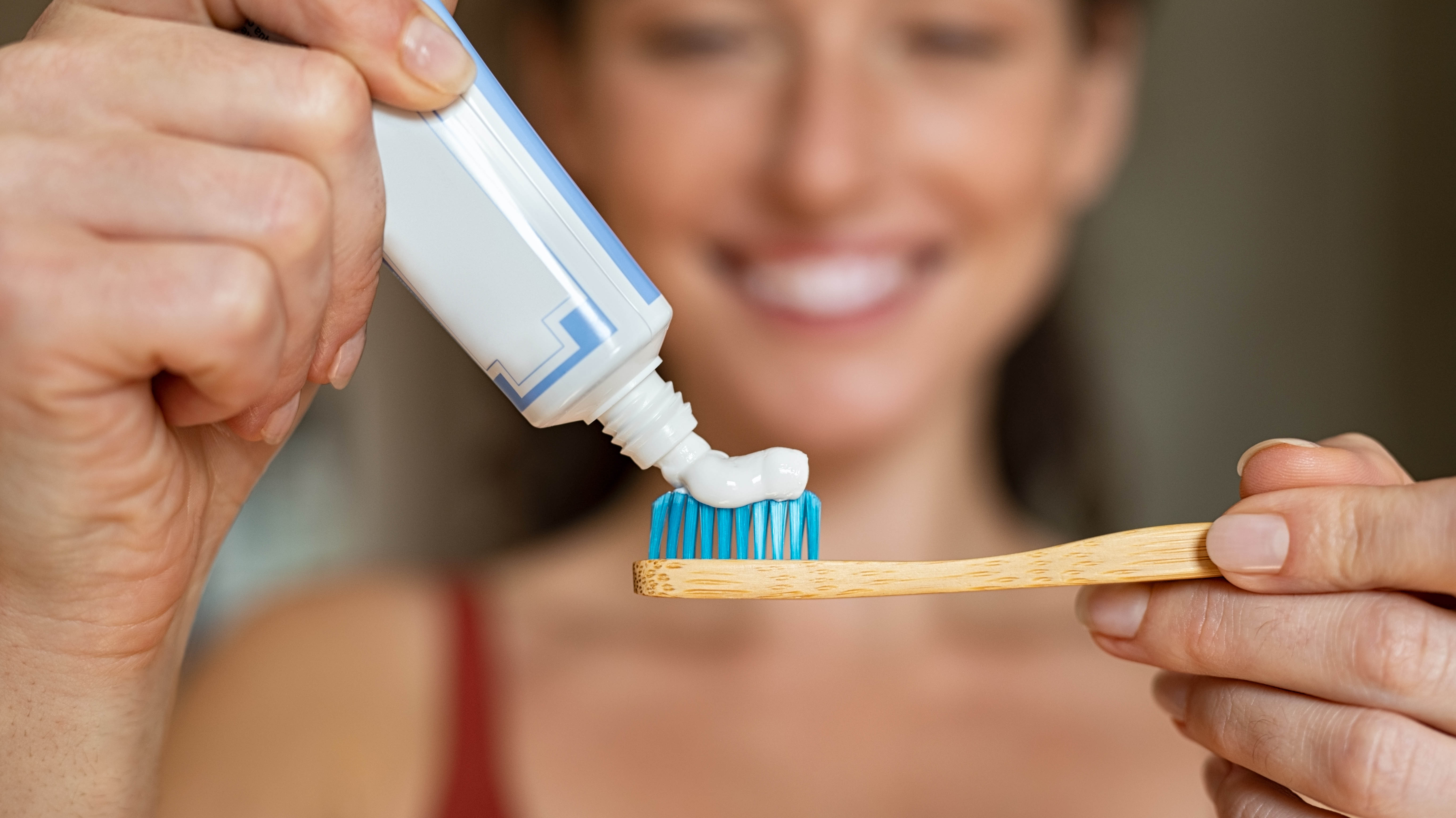 אישה מורחת משחת שיניים על מברשת שיניים