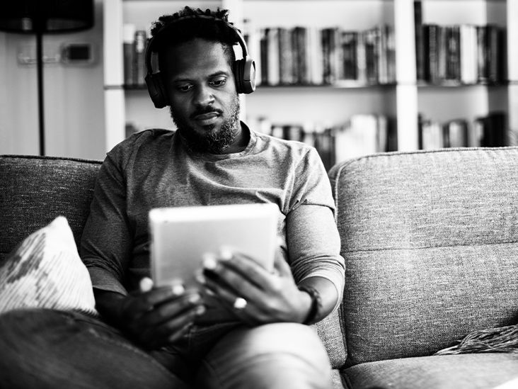 A man reads an iPad while wearing headphones