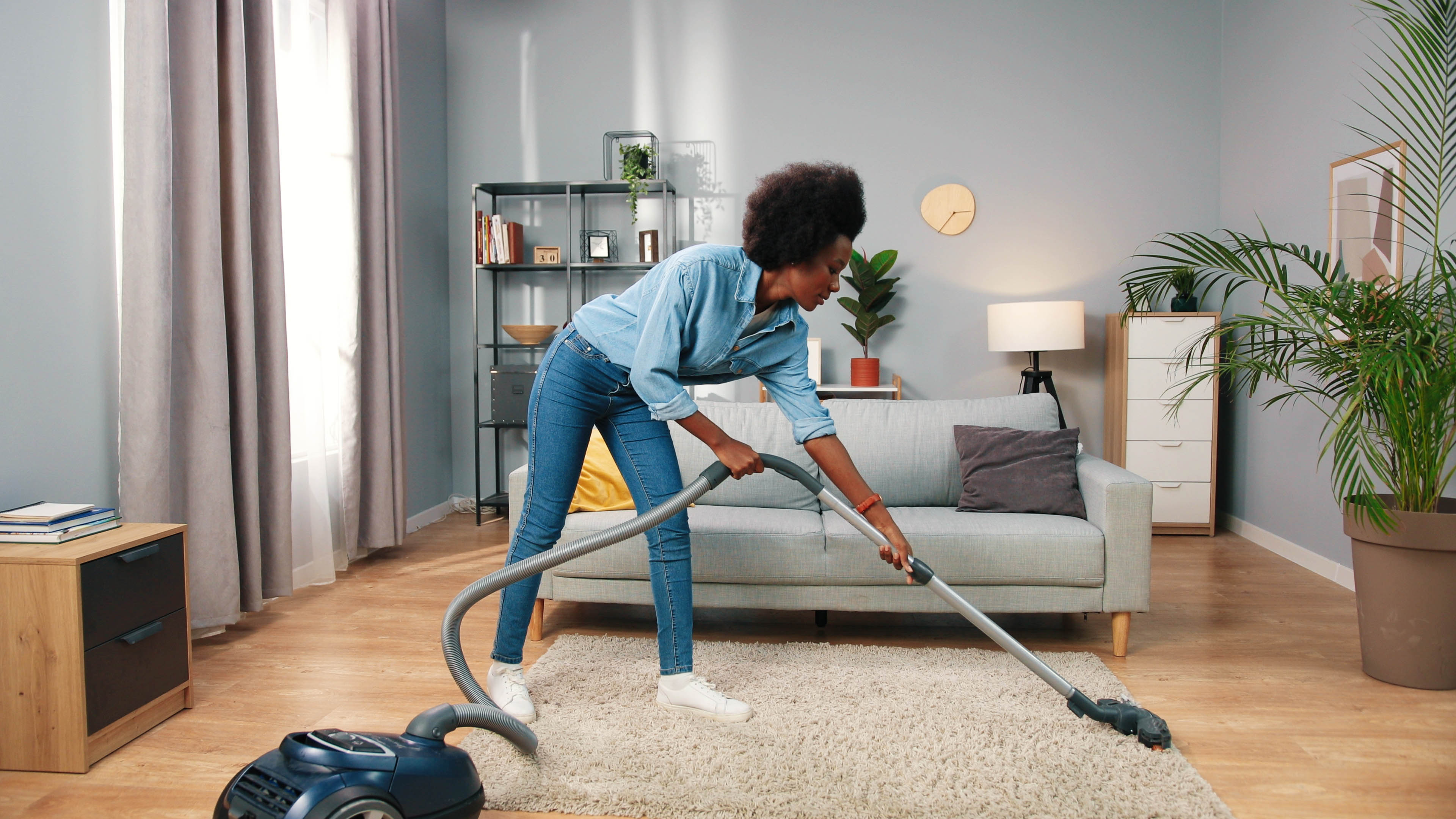 אישה שואבת שטיח בתוך הבית