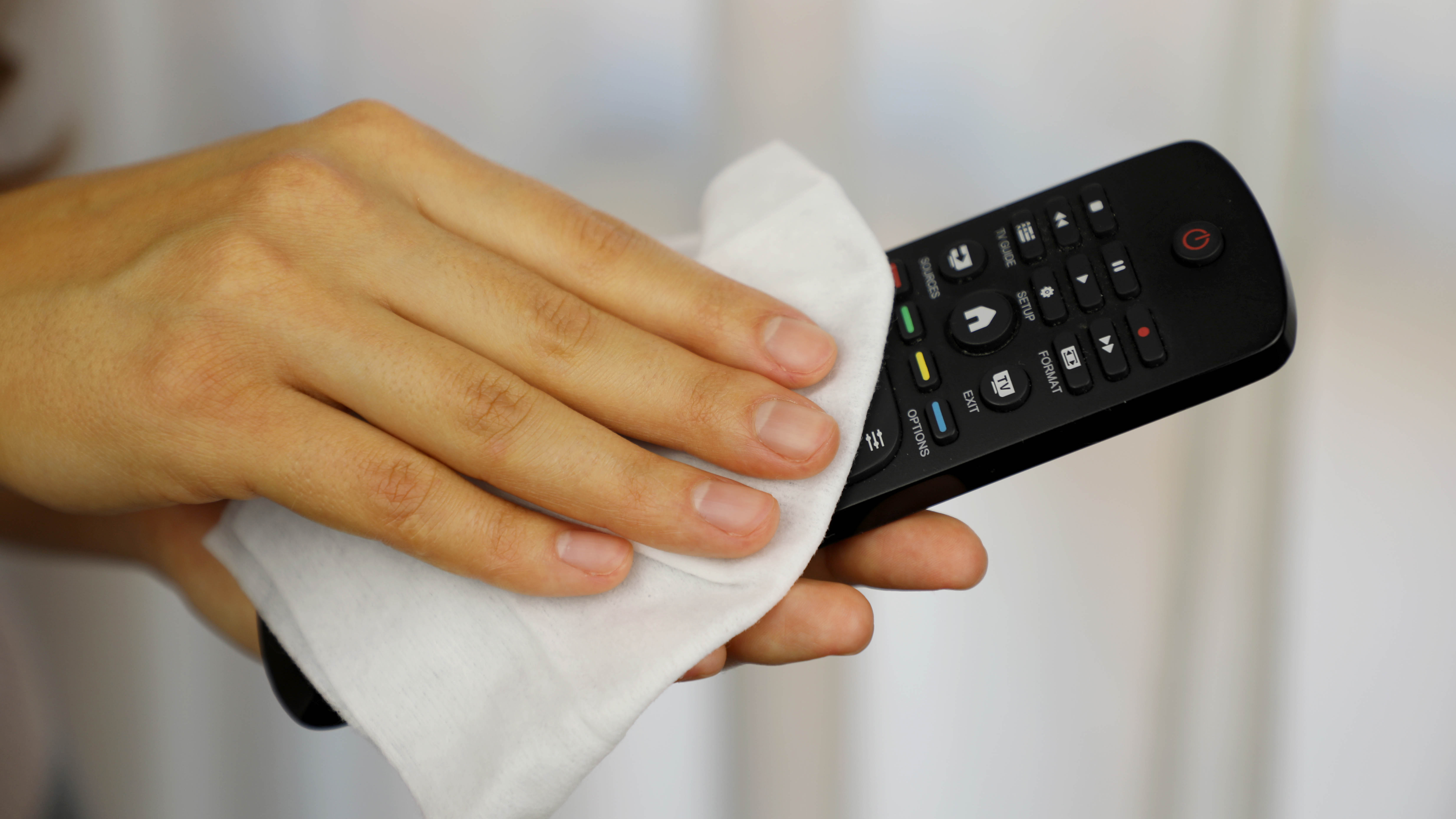 מישהו מנקה שלט רחוק עם מגבון