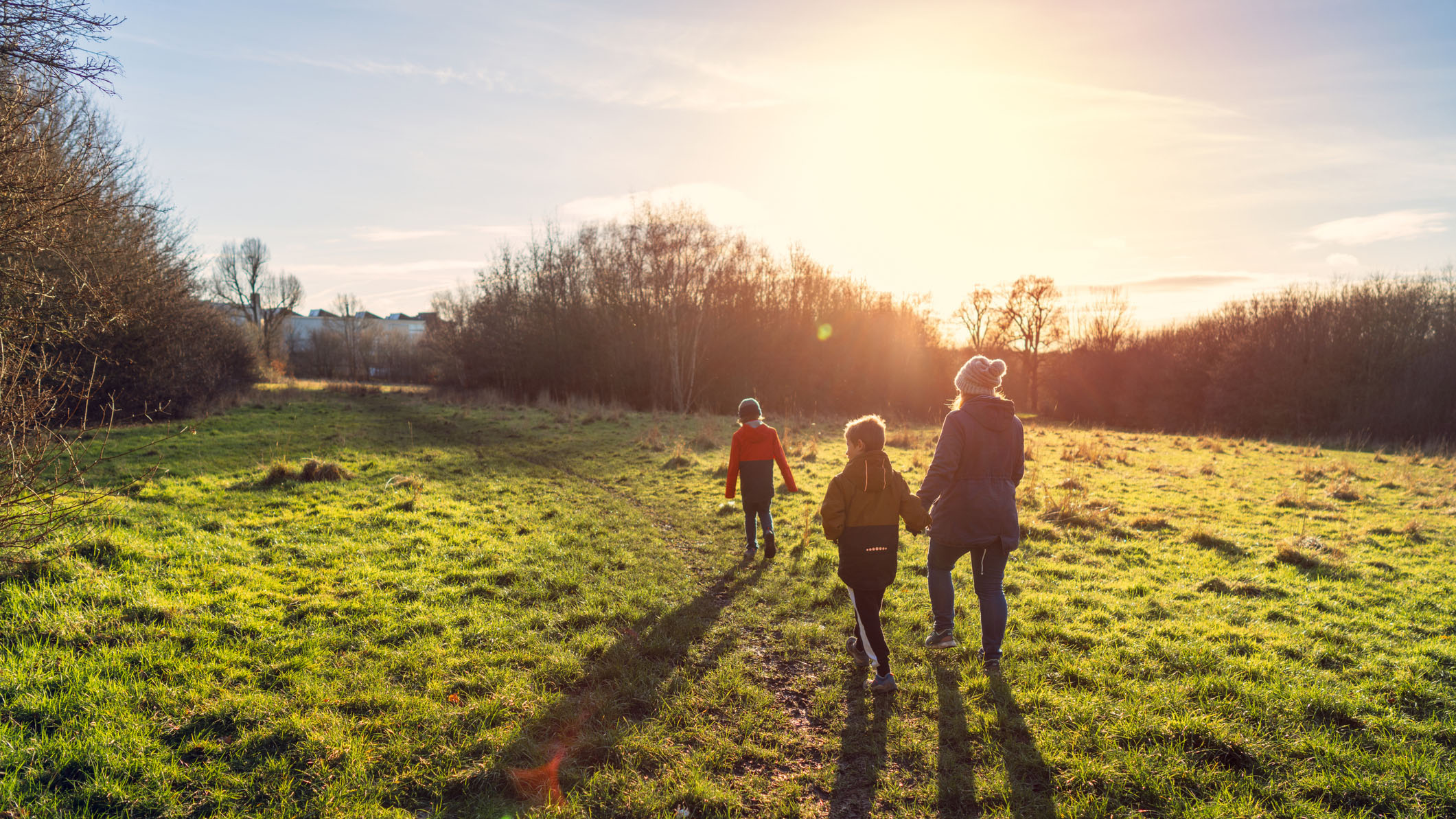 אישה ושני ילדים יוצאים לטיול מוקדם בבוקר בשמש חורפית כדי להגביר את המלטונין שלהם באופן טבעי
