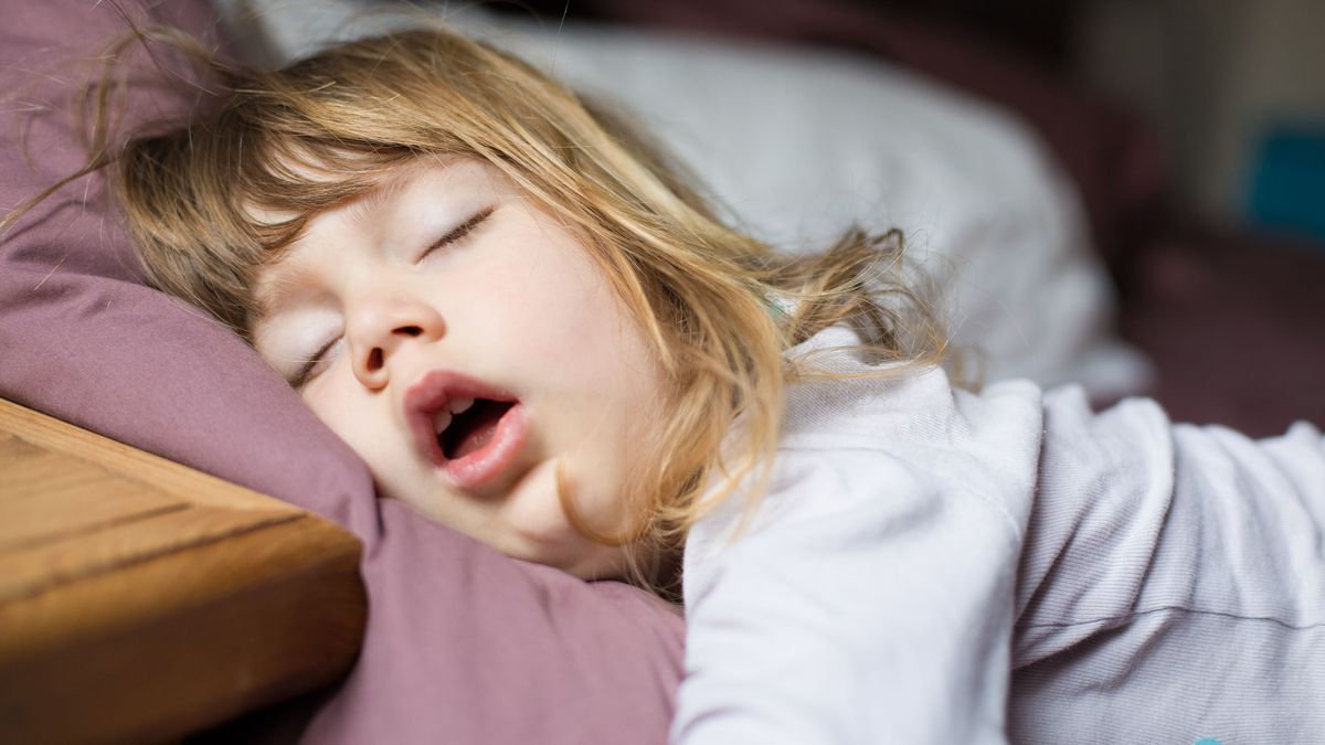 A little girl with blonde hair snores during sleep
