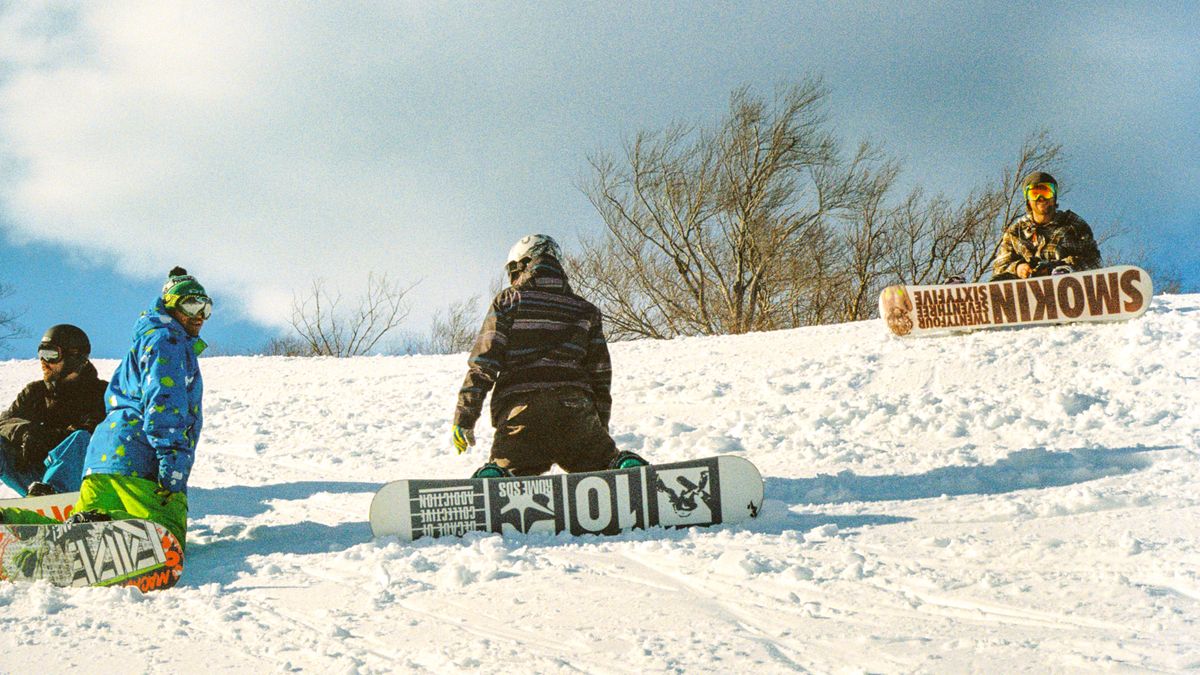A group of snowboarders hanging out and having fun on the mountain.