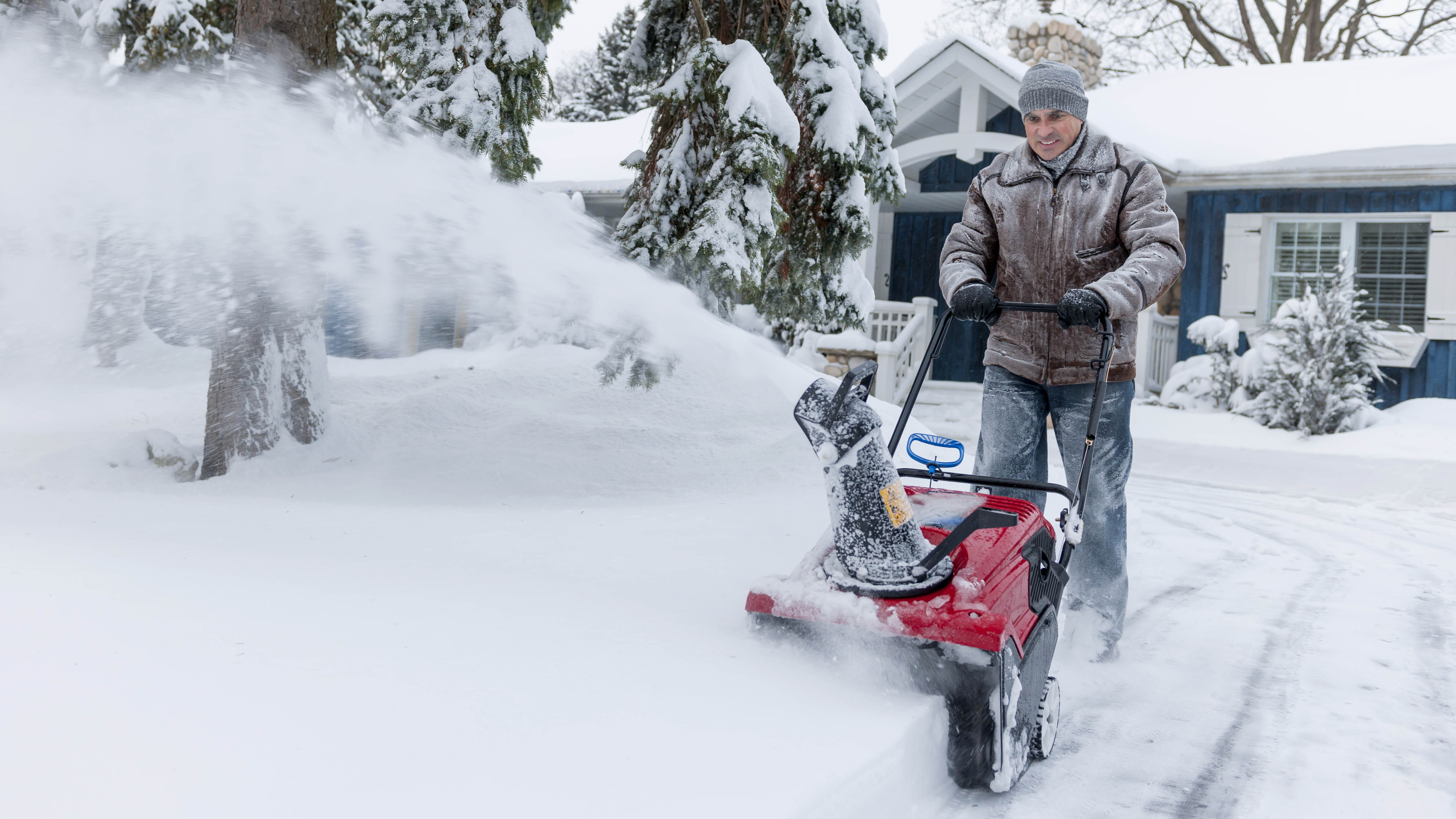 איש משתמש במפוח שלג בחניה