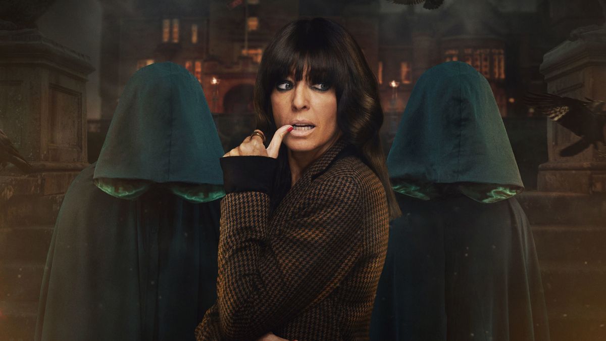 Claudia Winkleman posing in front of two hooded figures to promote The Traitors season 2