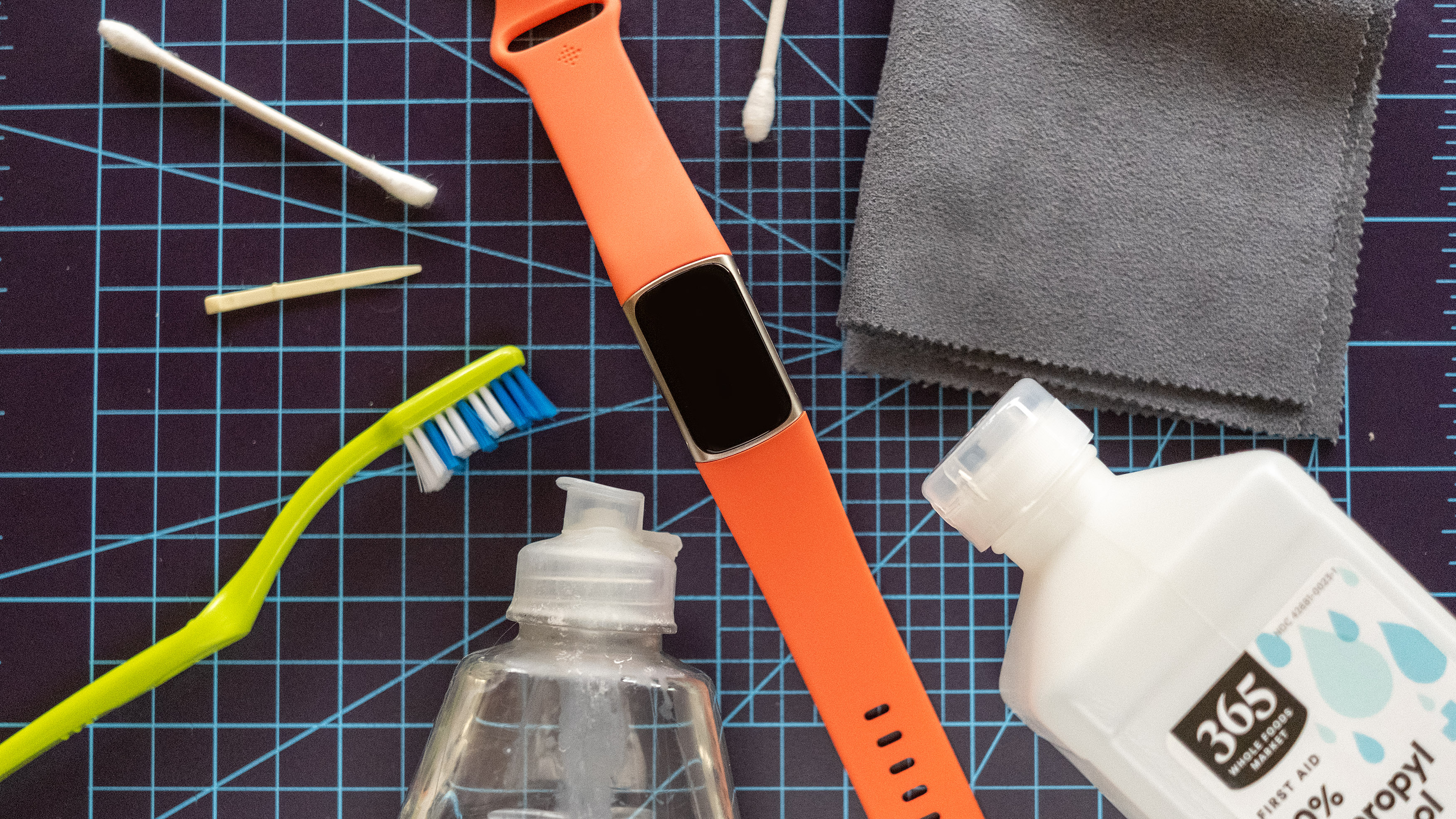 Fitbit Charge 6 מוצג ליד כלי ניקוי כולל מברשת שיניים ואלכוהול.