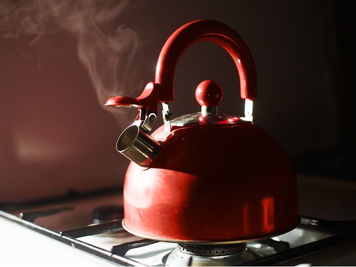 red kettle letting out steam on a stove