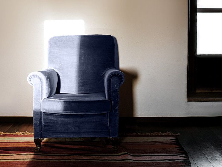 An empty armchair with the sun half shining on it.