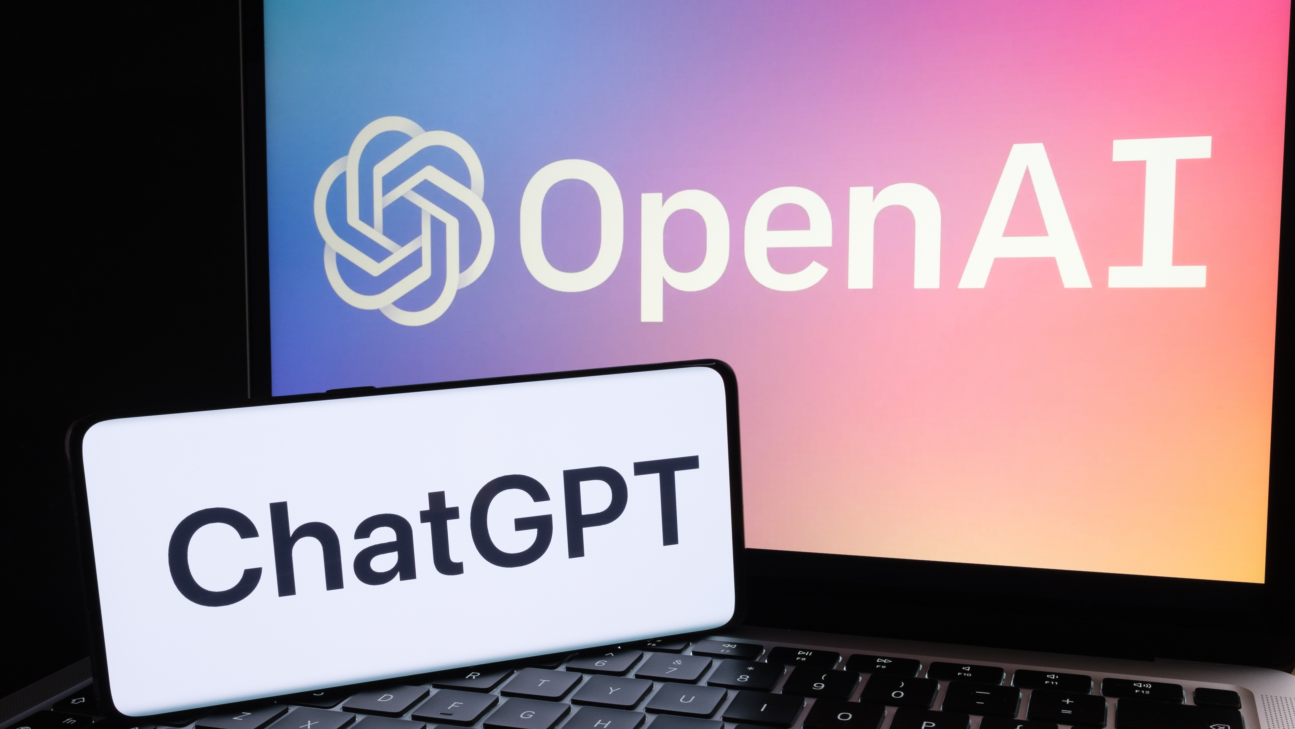 טלפון עם לוגו ChatGPT ומחשב נייד עם הלוגו של OpenAI