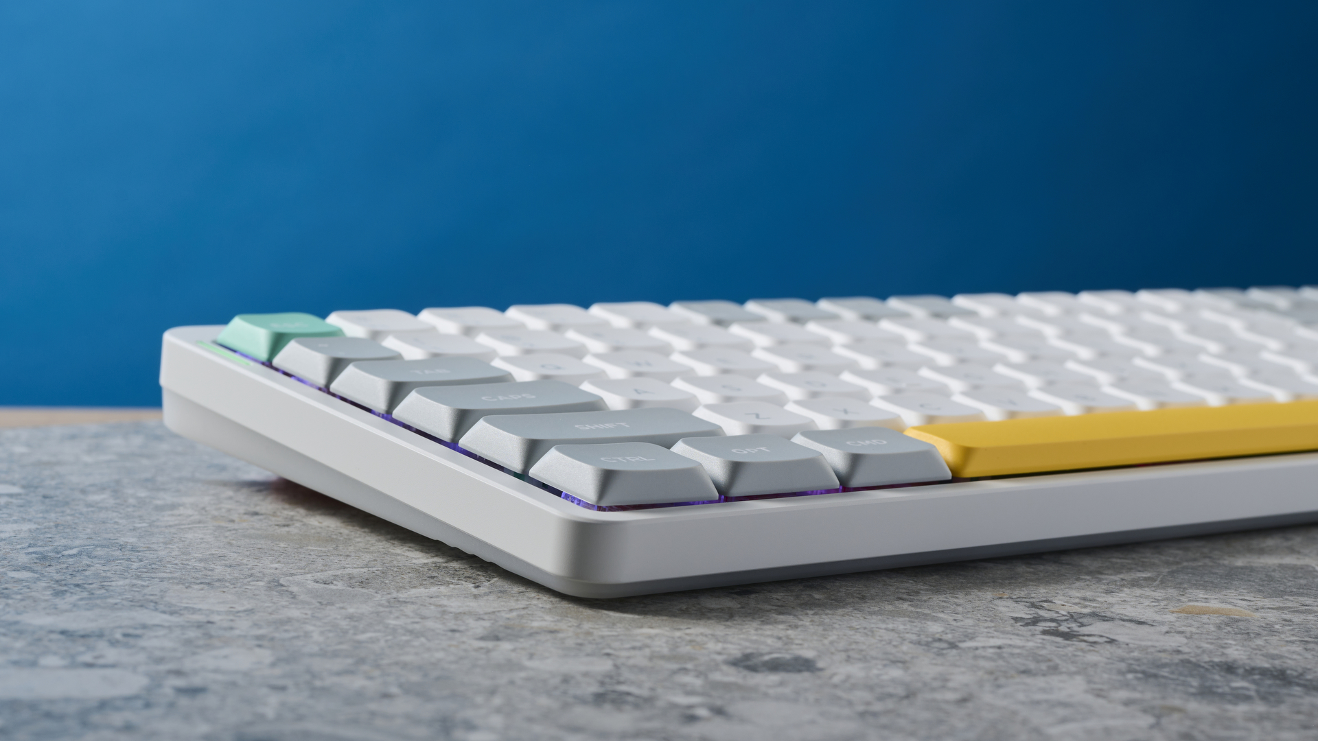 תמונה של ה-NuPhy Air75 V2 מהצד, על לוח אבן עם קיר כחול ברקע.