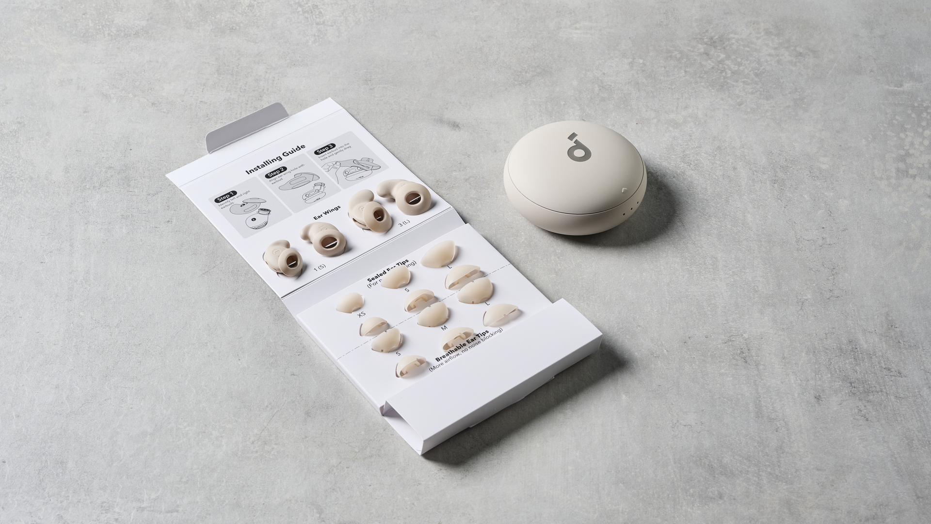 תמונה של נרתיק אוזניות Soundcore Sleep A20 על משטח אבן ליד סט אביזרי האוזניות החלופיות.