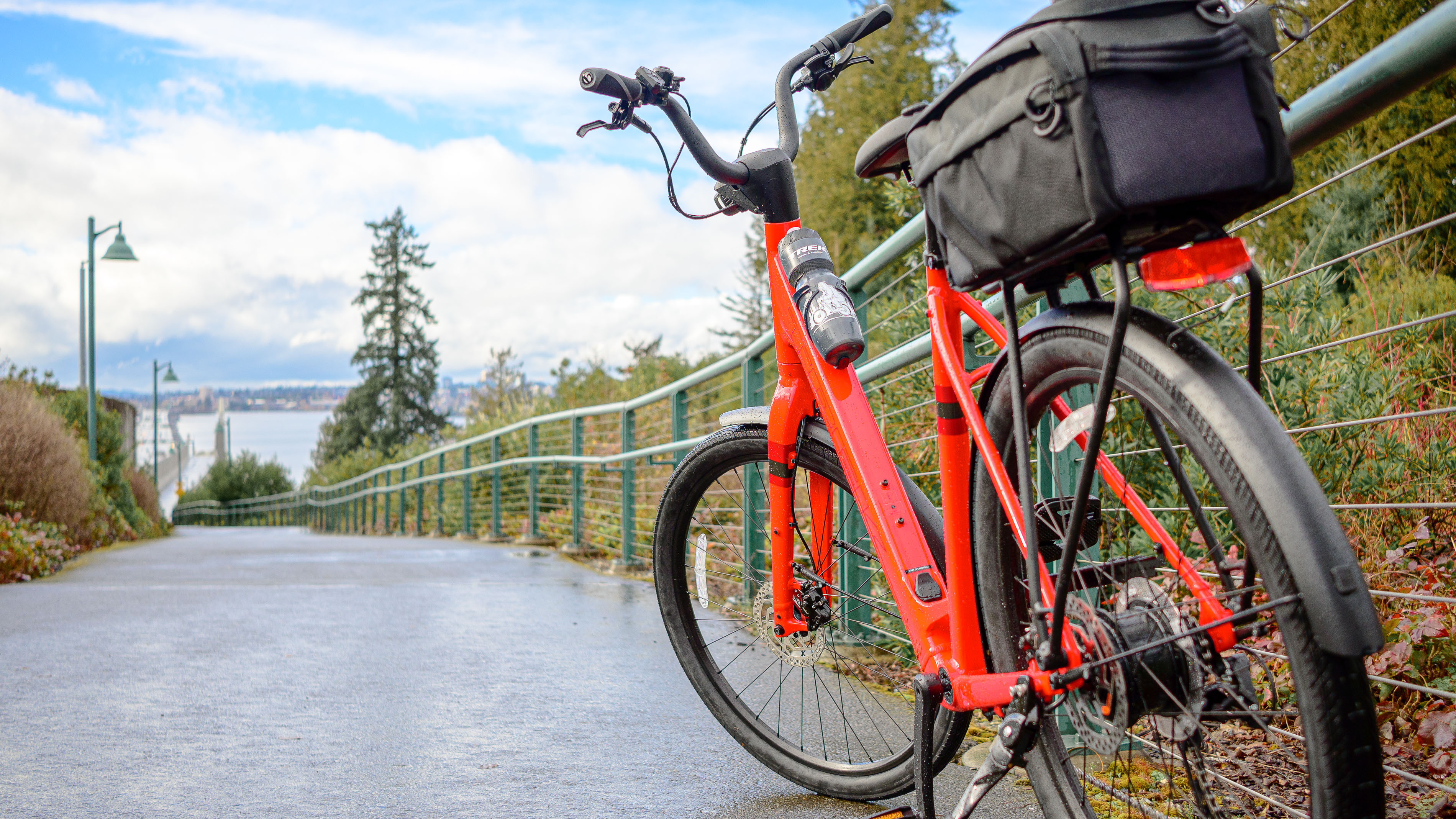אופניים חשמליים מסוג Trek Verve+ 1 Lowstep LT אדום עם שמיים כחולים מאחוריו.