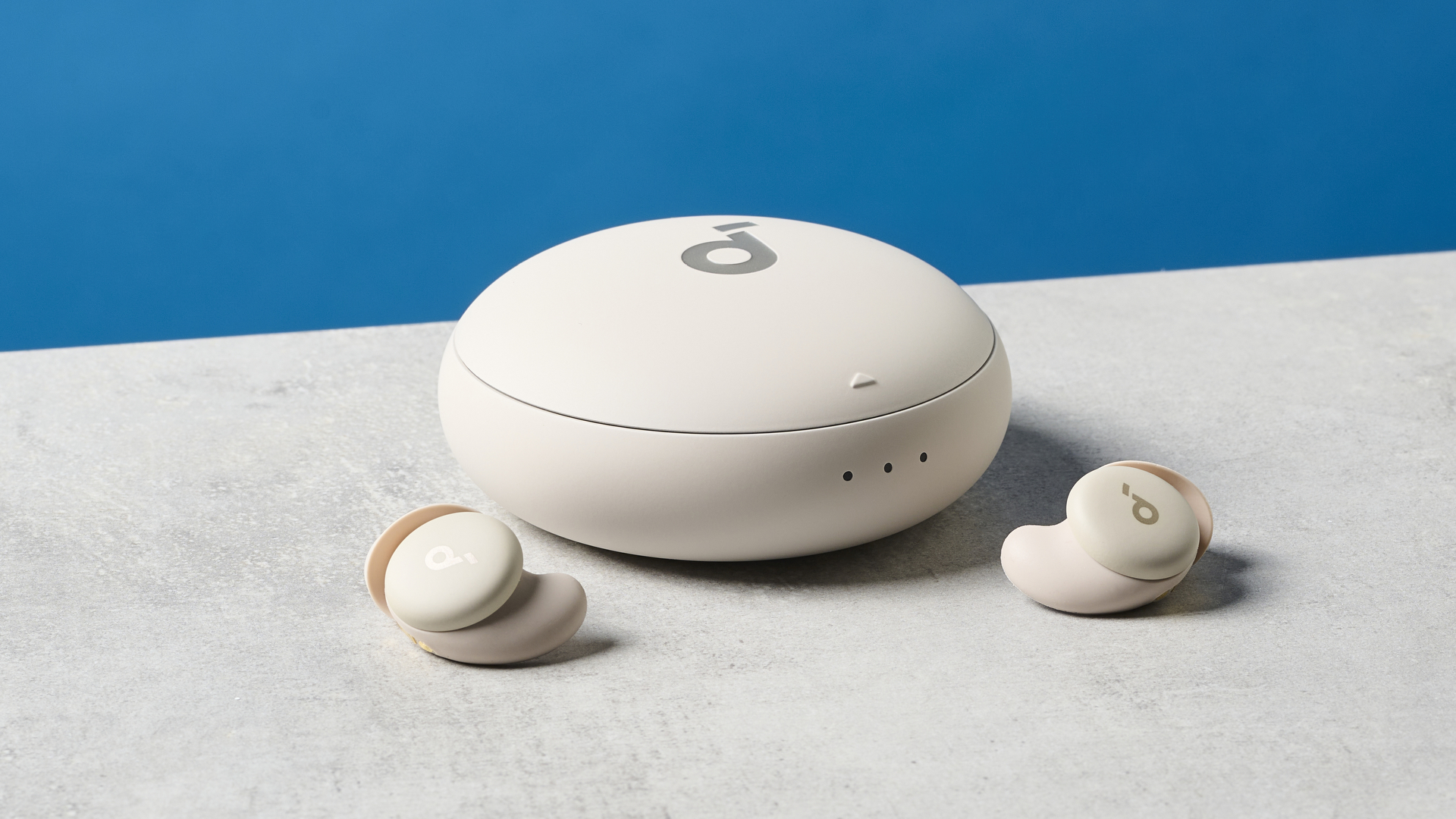 תמונה של אוזניות Soundcore Sleep A20 מחוץ וליד התיק שלהן על משטח אבן עם קיר כחול ברקע.