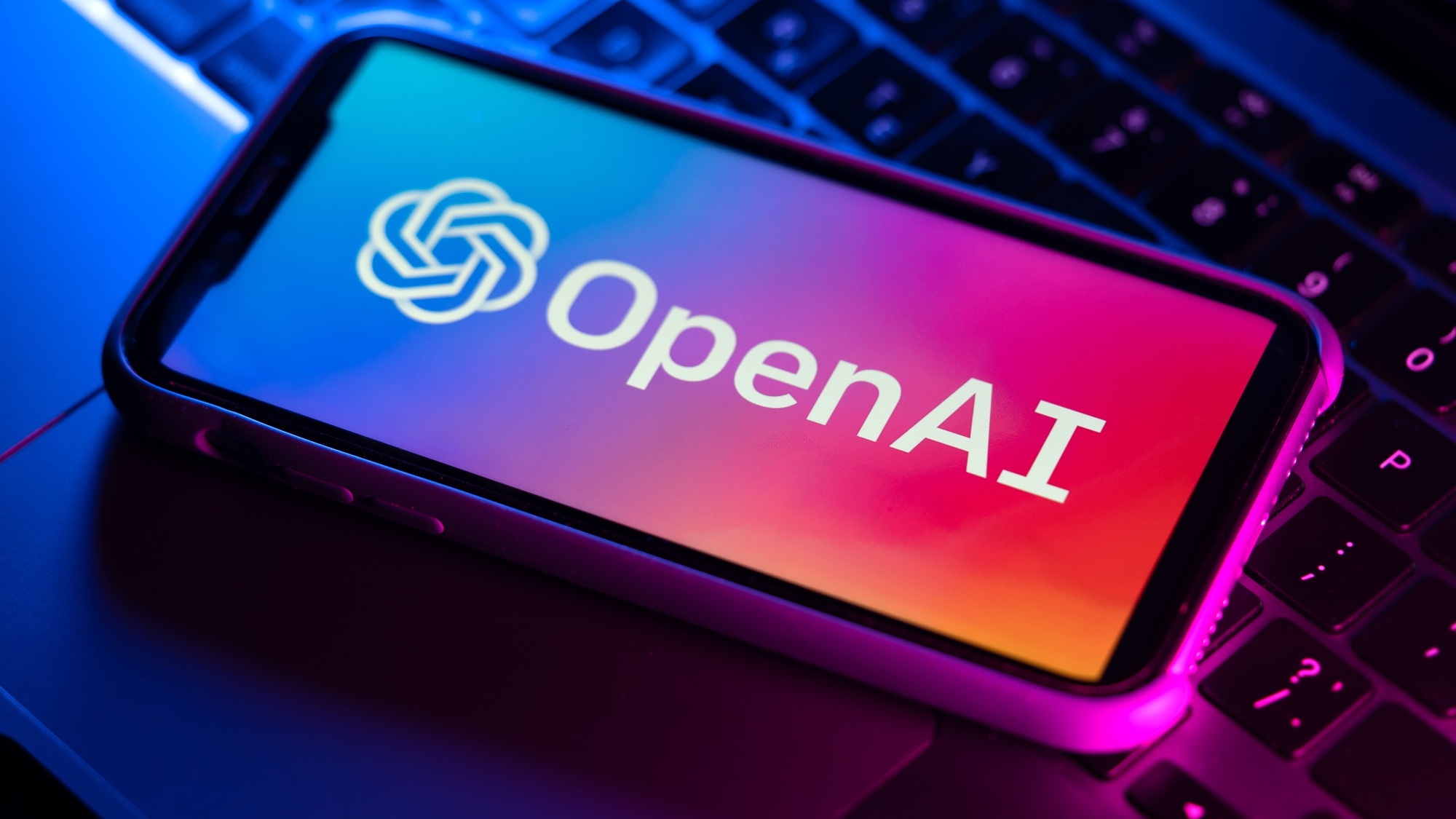 לוגו OpenAI בטלפון יושב על מקלדת מחשב נייד