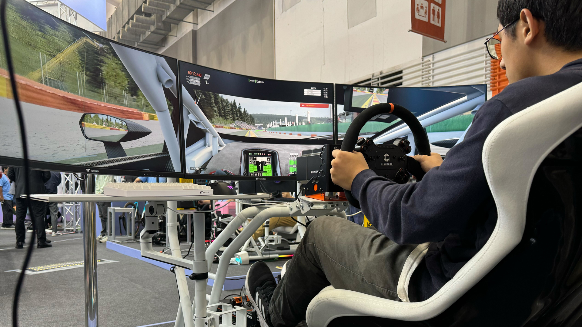 אדם משחק משחק מירוצים ב-Thermaltake GR500 Racing Sim Cockpit ב-Computex 2024.