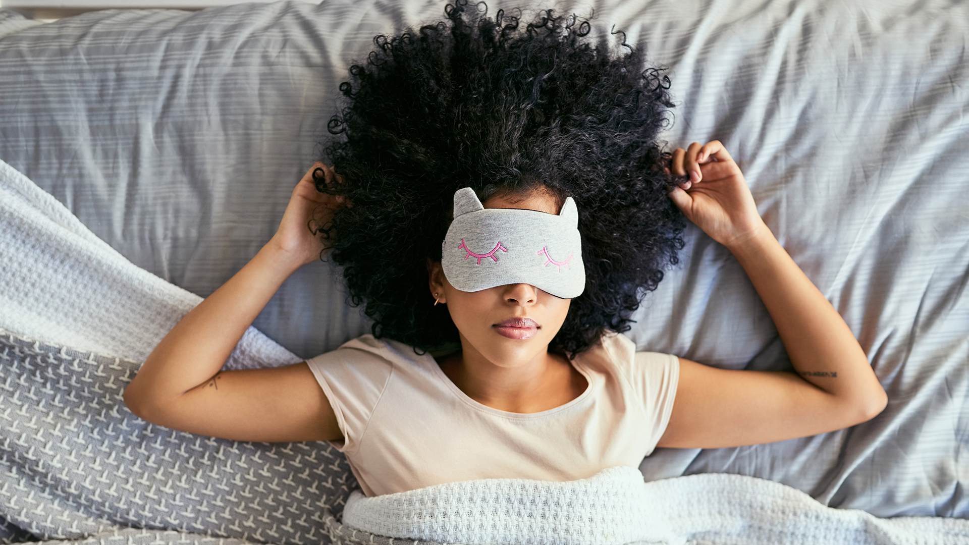 אישה שוכבת במיטה ישנה עם מסיכת עיניים
