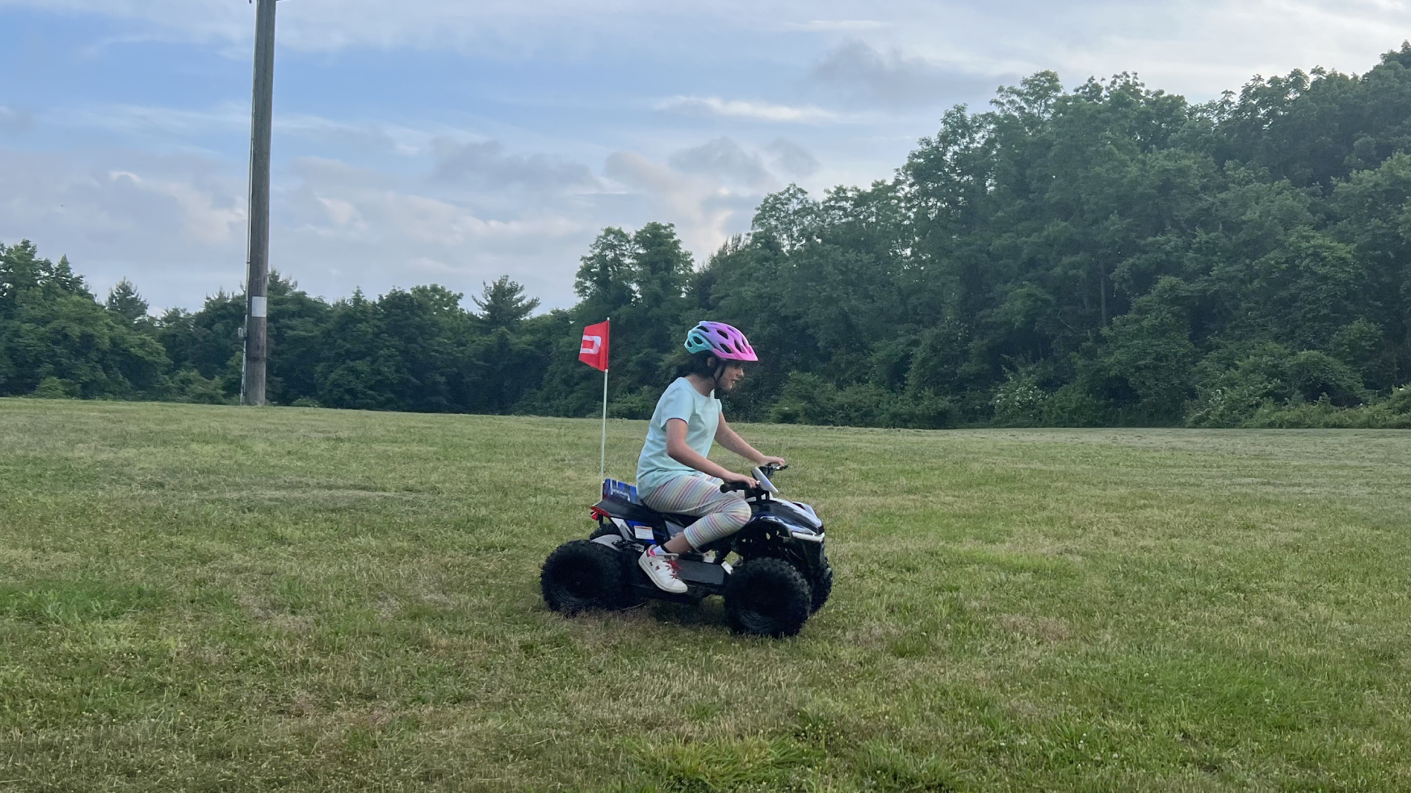 ילדה רוכבת על טרקטורון דרויד דרך שדה דשא