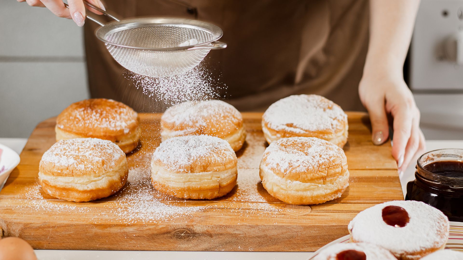 אדם מנפה אבקת סוכר על סופגניות