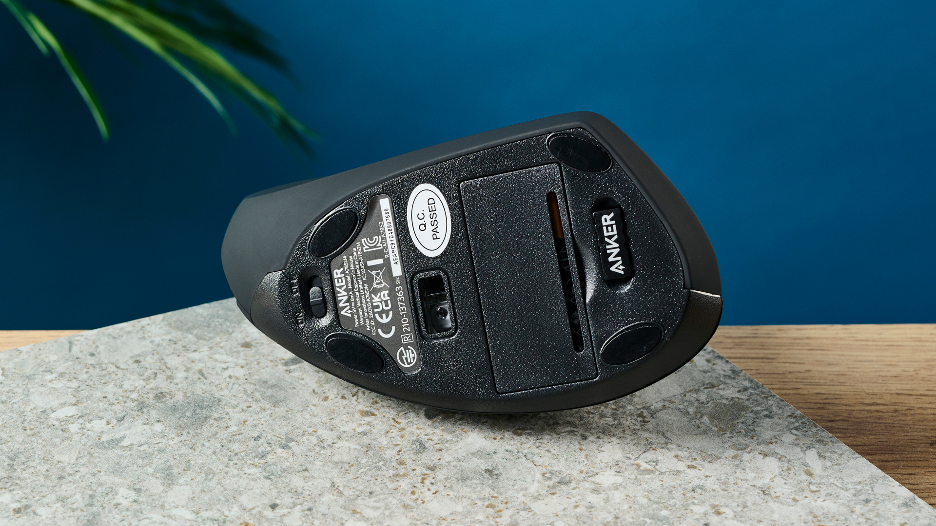 עכבר אנקר 2.4G אלחוטי אנכי ארגונומי על משטח אבן עם קיר כחול ברקע