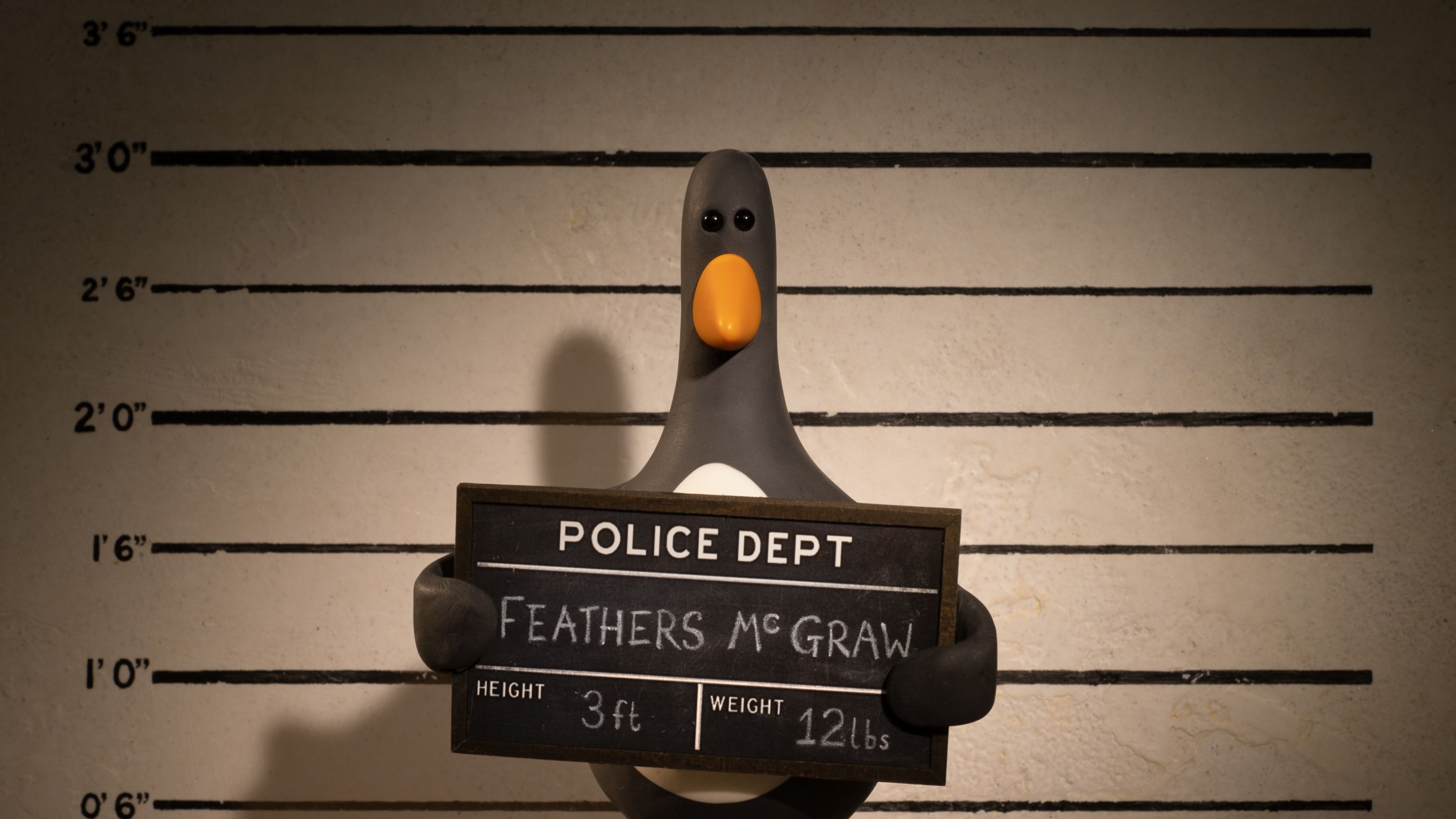 דמות הפינגווין Feathers McGraw מחזיקה שלט להרכב משטרתי 