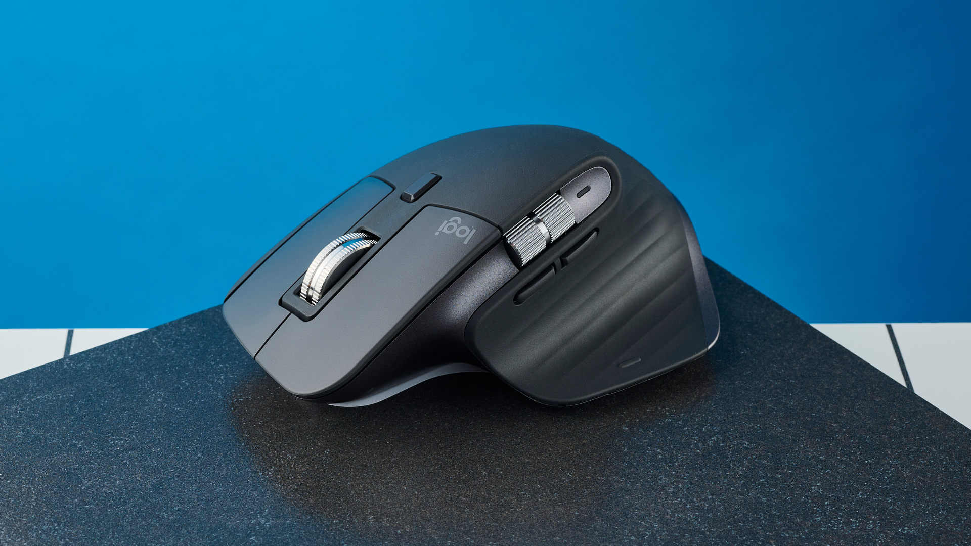 תמונה של Logitech MX Master 3S על צפחה שחורה על רקע כחול.
