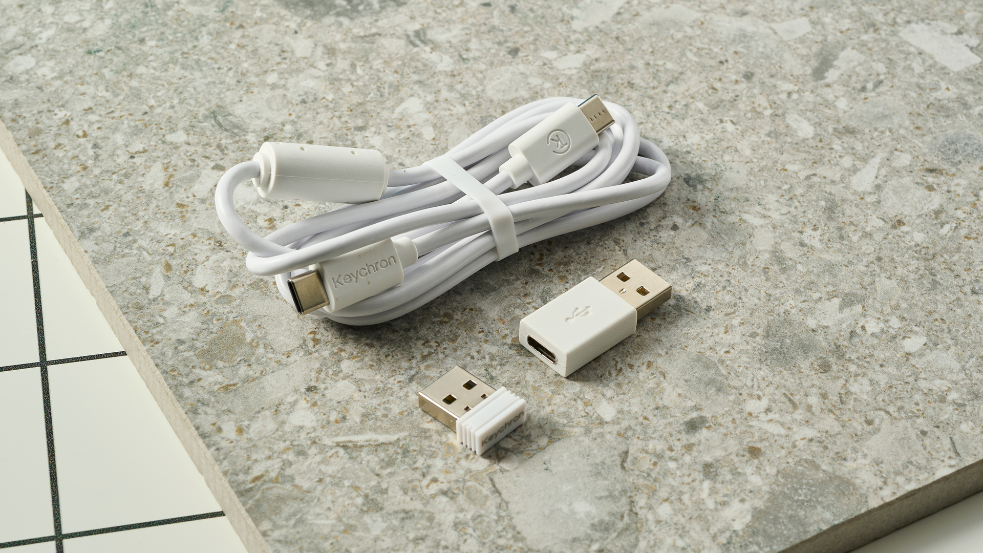 כבל טעינה ודונגל 2.4GHz ומתאם USB-C על שולחן לבן