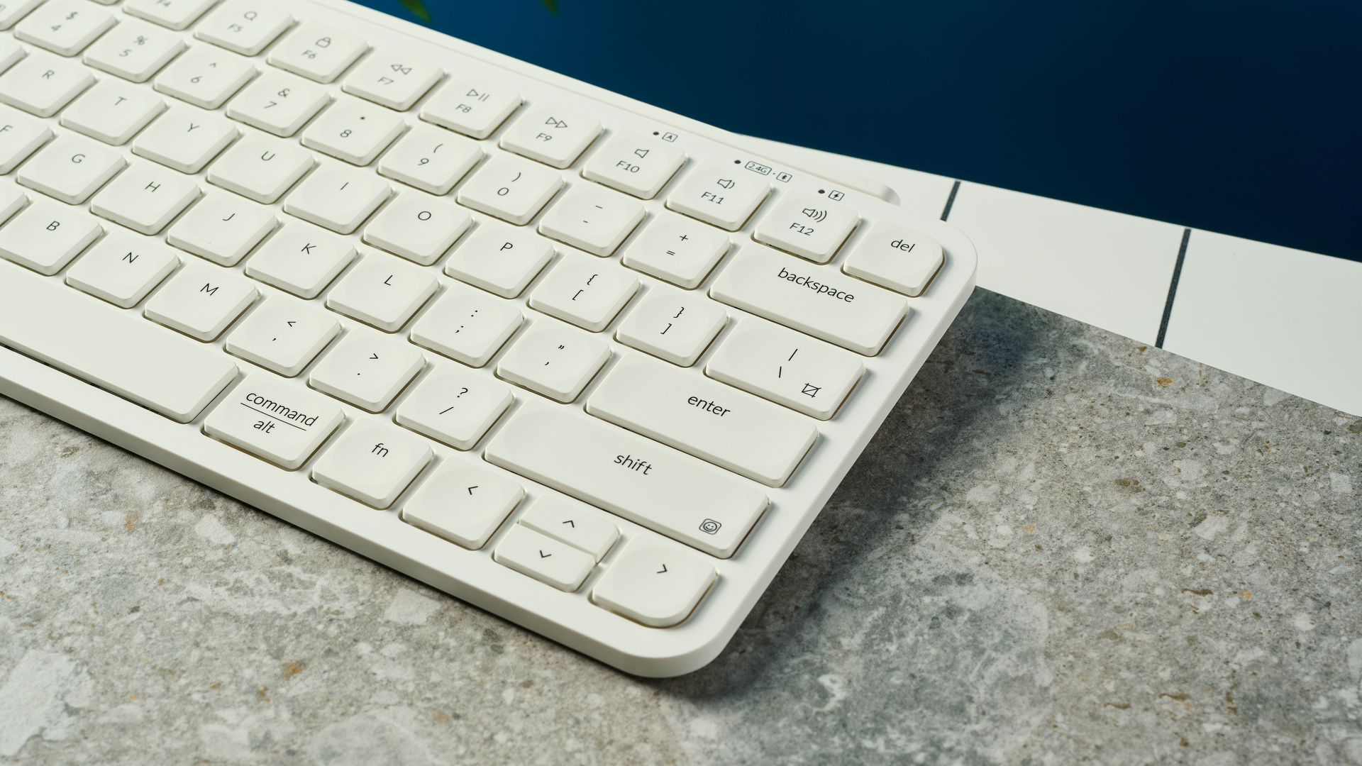 צילום מקרוב של מקלדת Bluetooth אלחוטית לבנה מונחת על שולחן לבן נקי עם צל מתחתיו