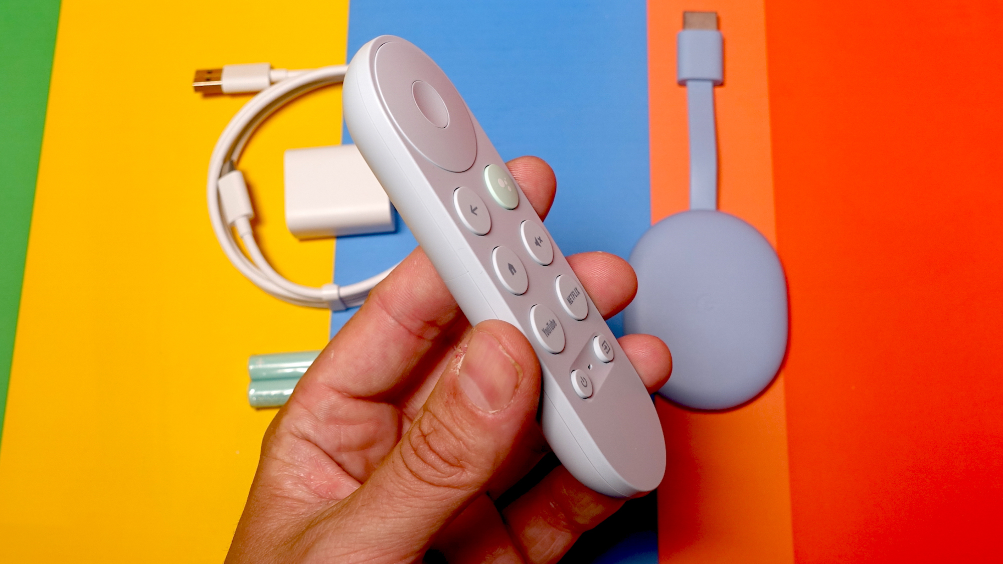 Chromecast עם שלט Google TV 4K ביד מעל הדונגל והכבלים