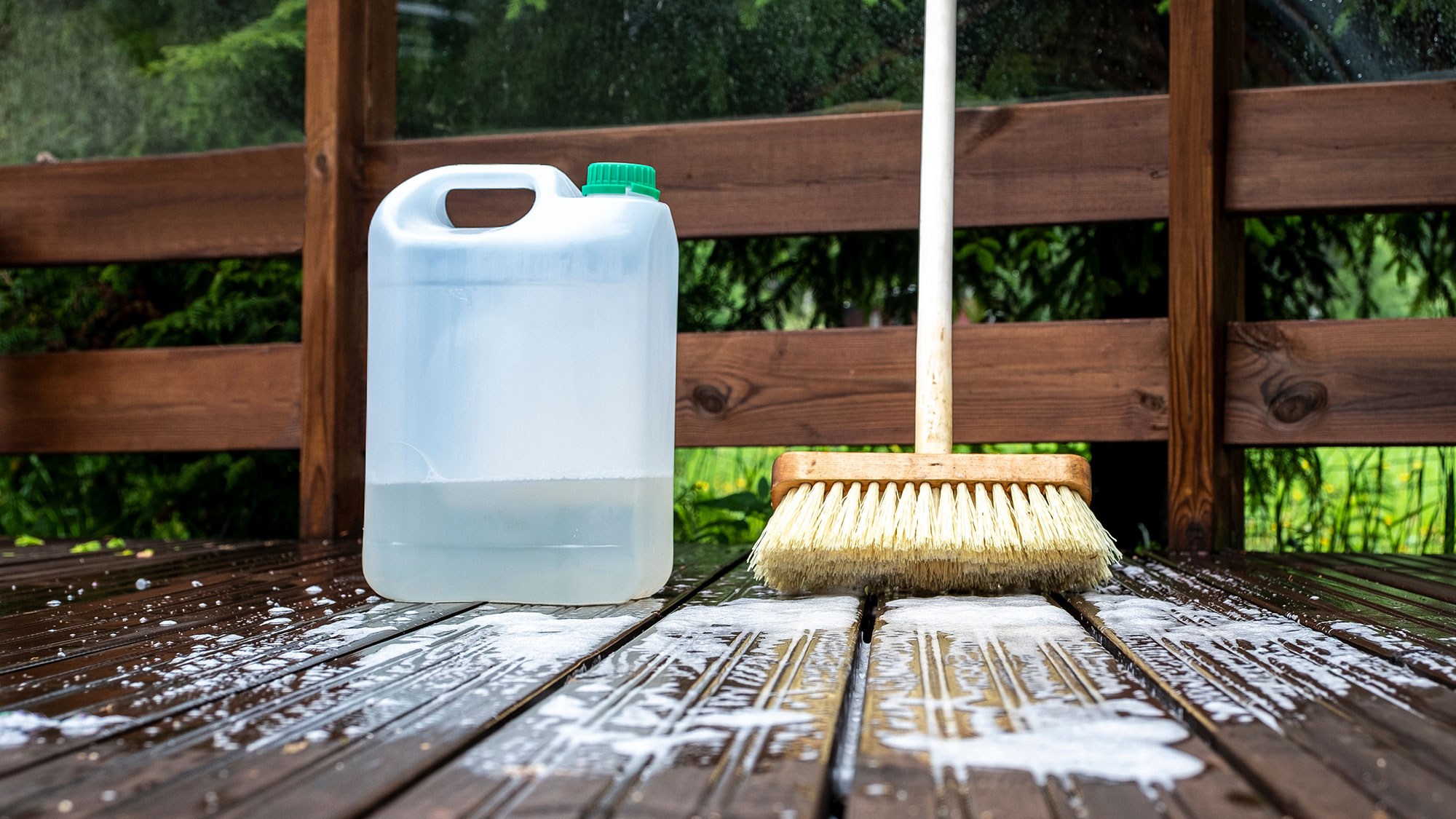 מברשת ומיכל פלסטיק עם חומר ניקוי על דק עץ