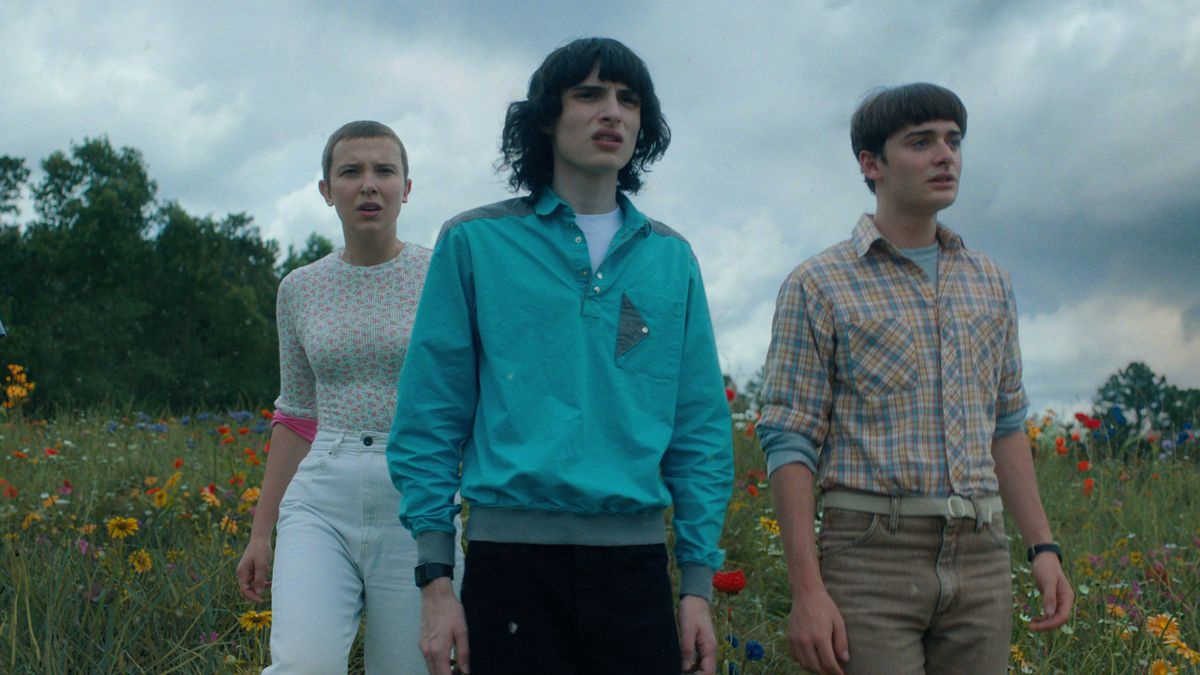 Eleven, Mike, and Will (L-R) stand in a field in