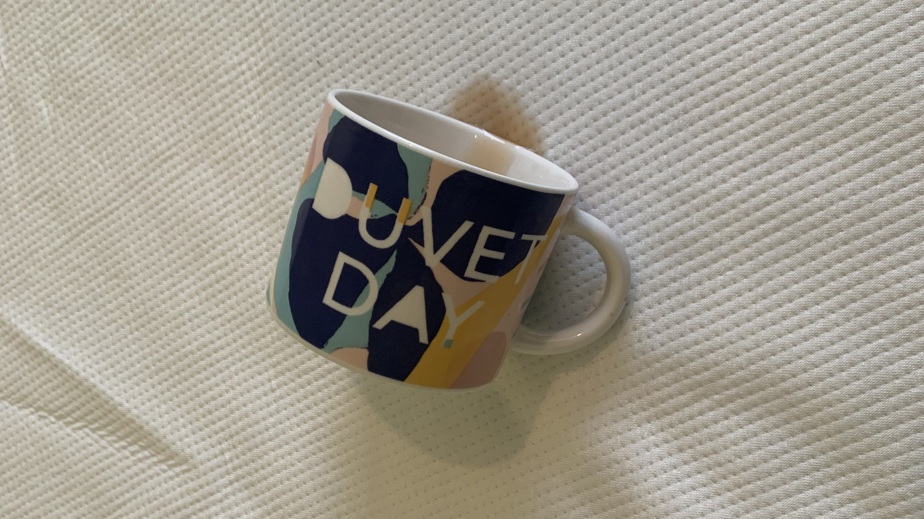 תמונה מראה תה שחור נשפך מכוס על כיסוי של מזרון לבן