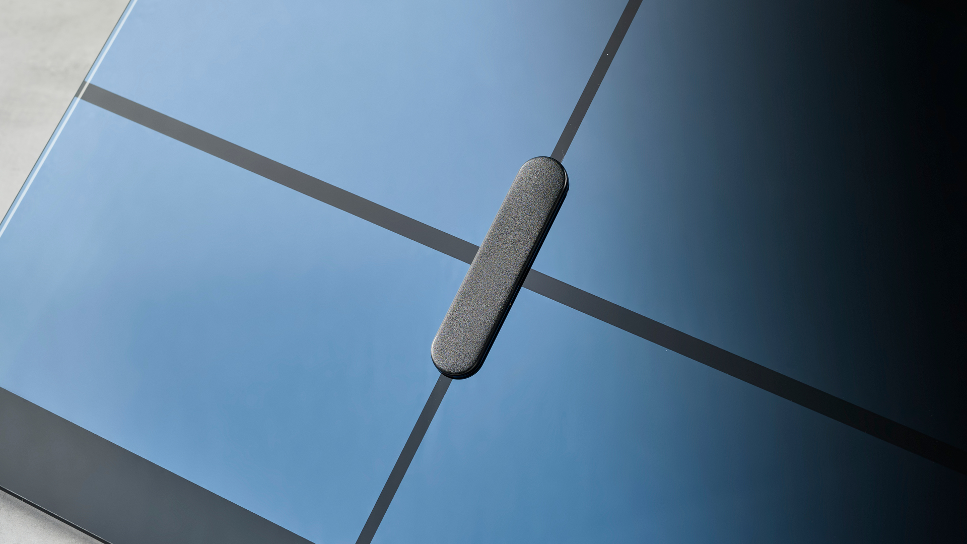 משקל חכם מלוטש ונקי למראה עם גימור זכוכית מחוסמת ועיצוב בצורת צלב על גבי הזכוכית, כמעט כחול בתאורת הסטודיו, מונחת על שולחן