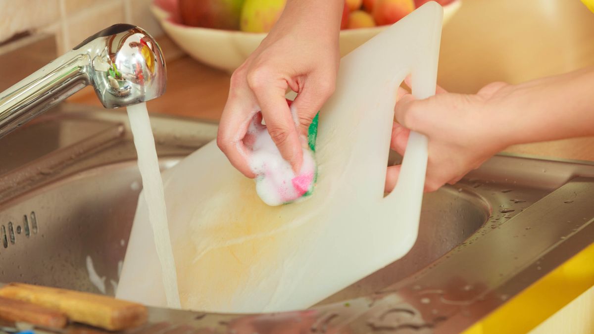 Woman washing a plastic cutting board