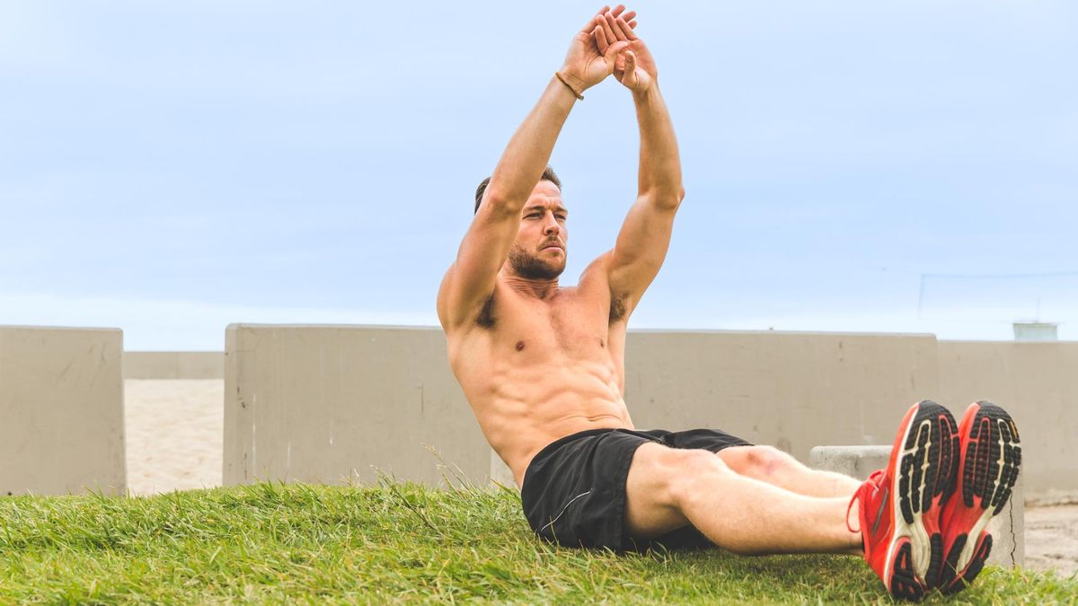 Man performing the crunch exercise outdoors on exercise mat during workout