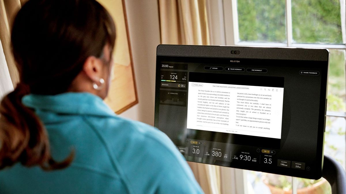 A woman reads a Kindle ebook on a Peloton display