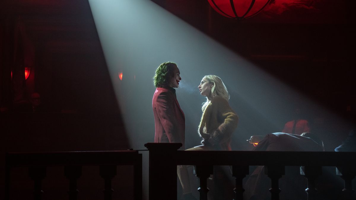 Arthur Fleck (Joaquin Phoenix) and Lee Quinzel (Lady Gaga) face one another lit by a spotlight in "Joker: Folie A Deux"