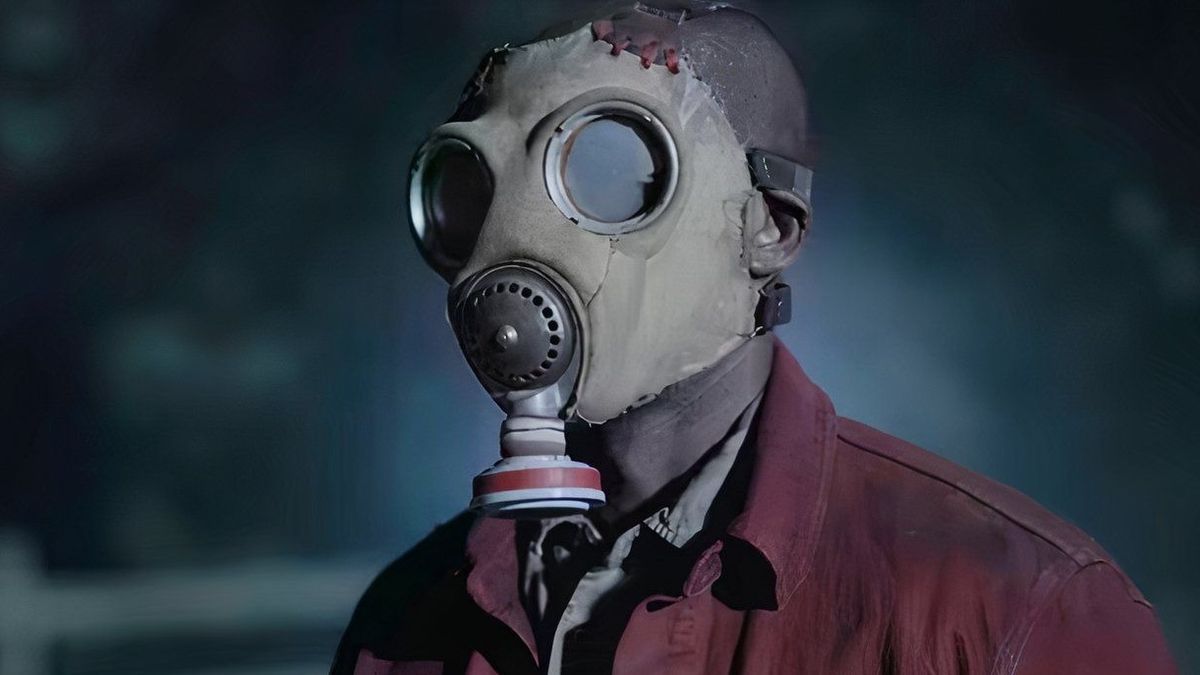 Person wearing creepy grey gas mask and maroon jacket in a scene from James Wan's TV horror series Teacup season 1