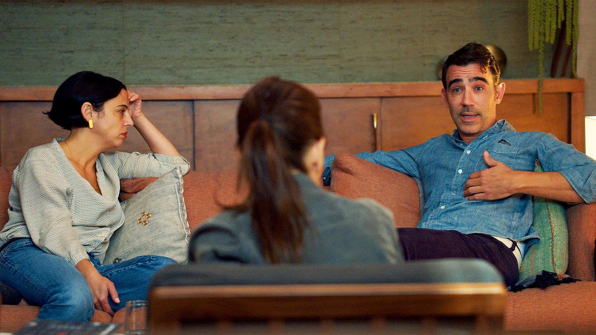 A man (R) and a women (L) sit in Couples Therapy with therapist Orna Guralnik with her back to the camera between them.