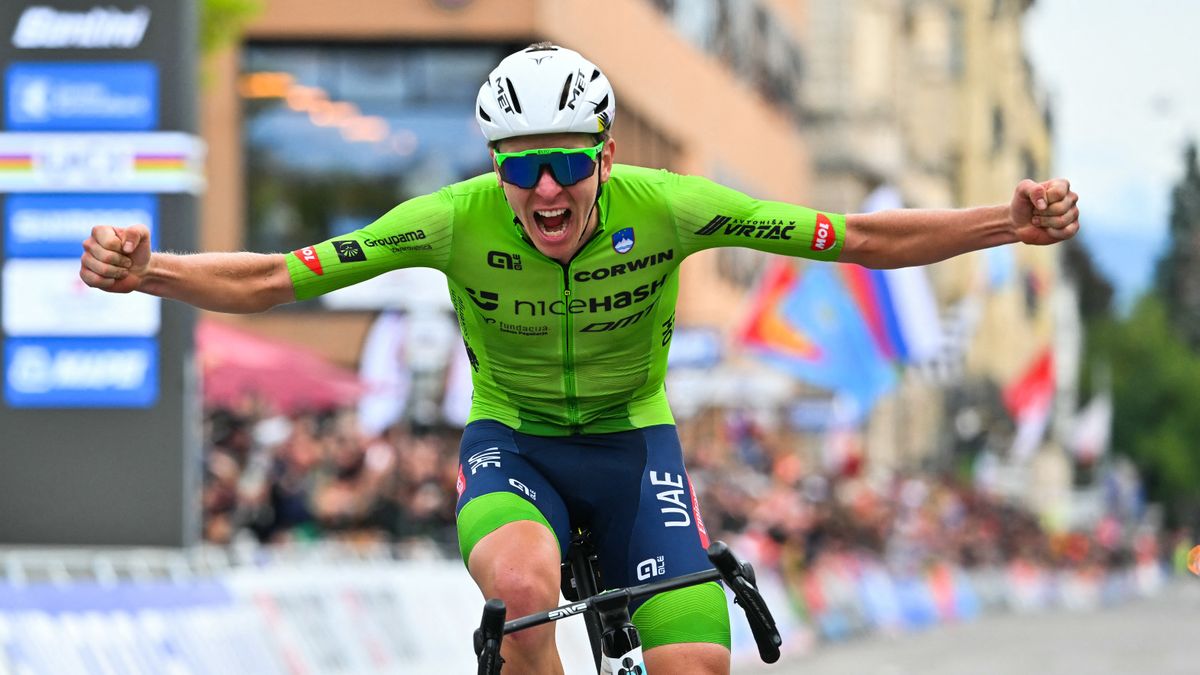 Slovenia's Tadej Pogacar, wearing lime green jersey, celebrates as he crosses the finish line on his bike ahead of the next big race: the Giro dell'Emilia 2024