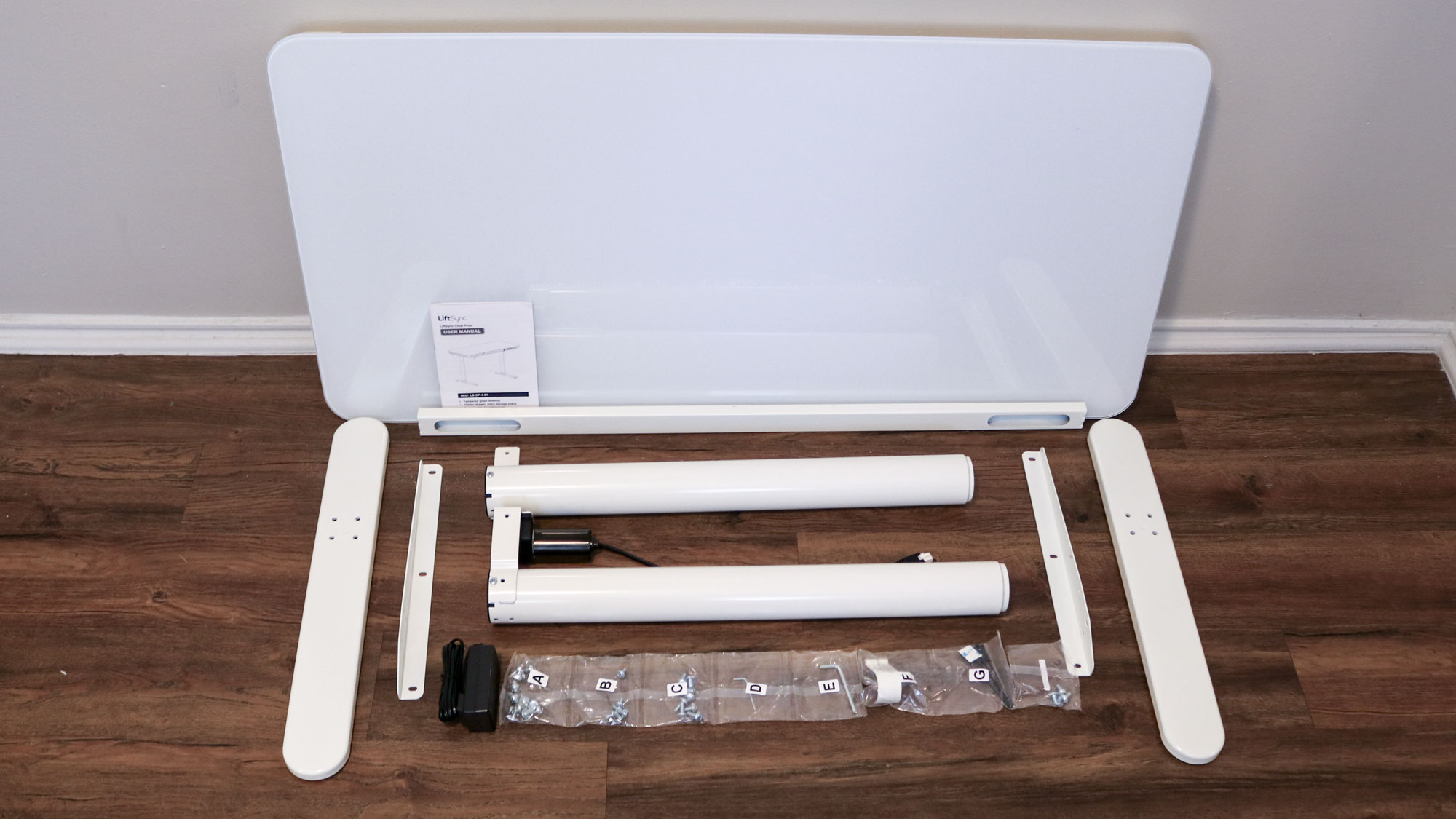 שולחן הכתיבה העמיד LiftSync Clear Plus לא ארוז עם כל החלקים על הרצפה