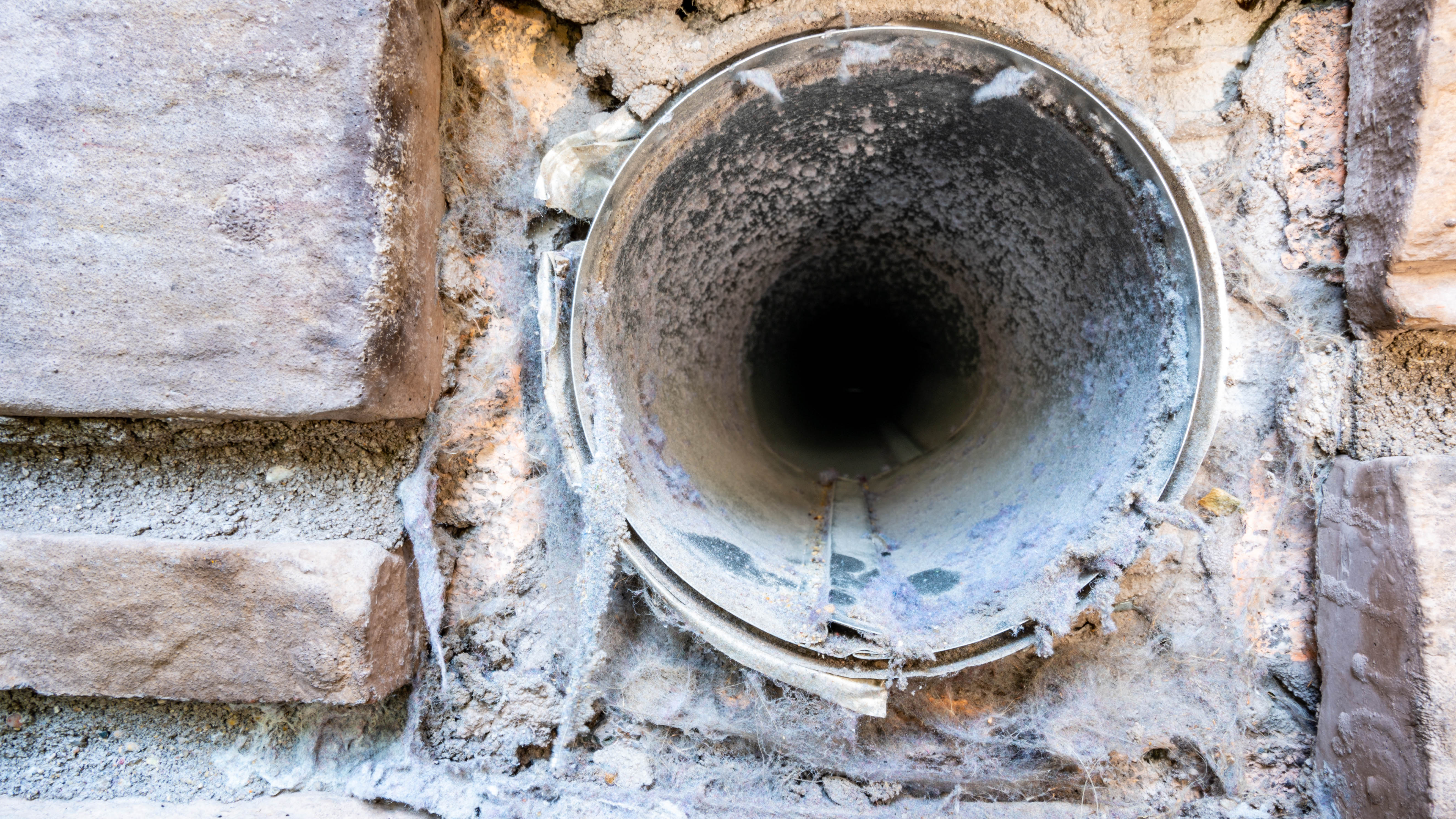 החלק החיצוני של פתח אוורור מייבש כביסה מלוכלך אשר מלא במוך