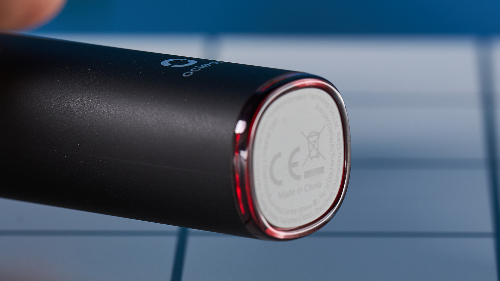 מברשת שיניים חשמלית שחורה עם מסך מגע קטן וראש מברשת שיניים כחול ומעמד טעינה מרובע