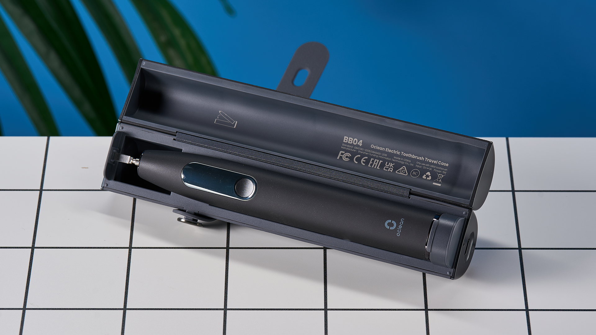 מברשת שיניים חשמלית שחורה עם מסך מגע קטן וראש מברשת שיניים כחול ומעמד טעינה מרובע