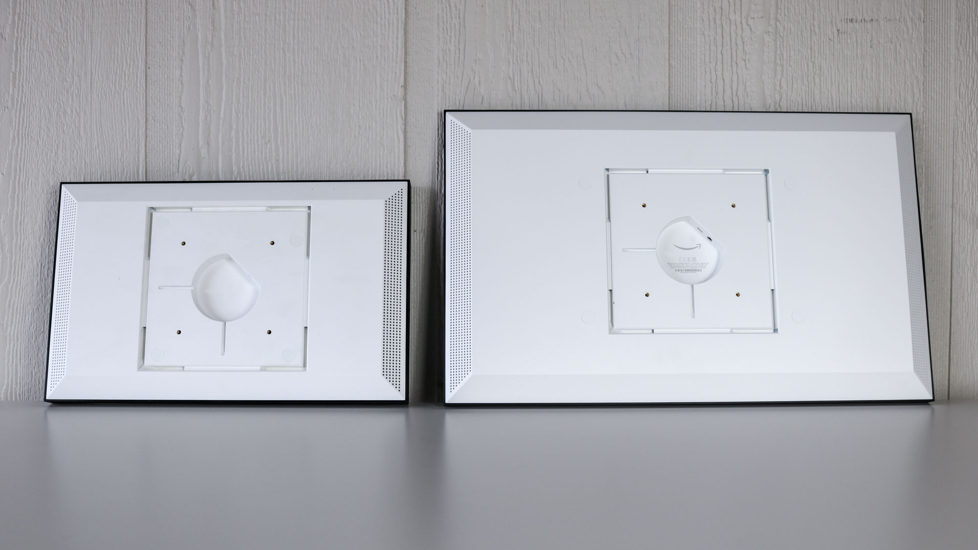 ה-Echo Show 15 ליד ה-Echo Show 21 החדש על שולחן המציג את גזרות ההרכבה ומיקומי תקע החשמל שלהם