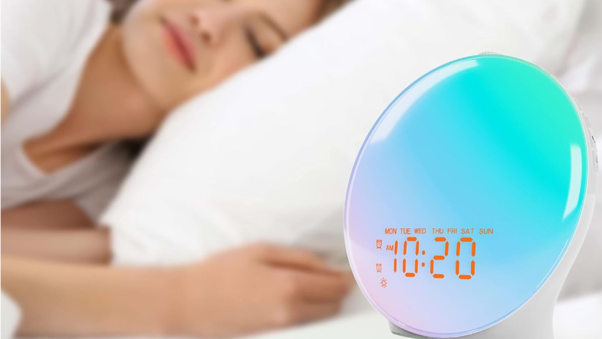 כחול וסגול JALL Wake-Up Light זריחה מעורר על ליד המיטה ליד אישה במיטה ישנה על הצד.