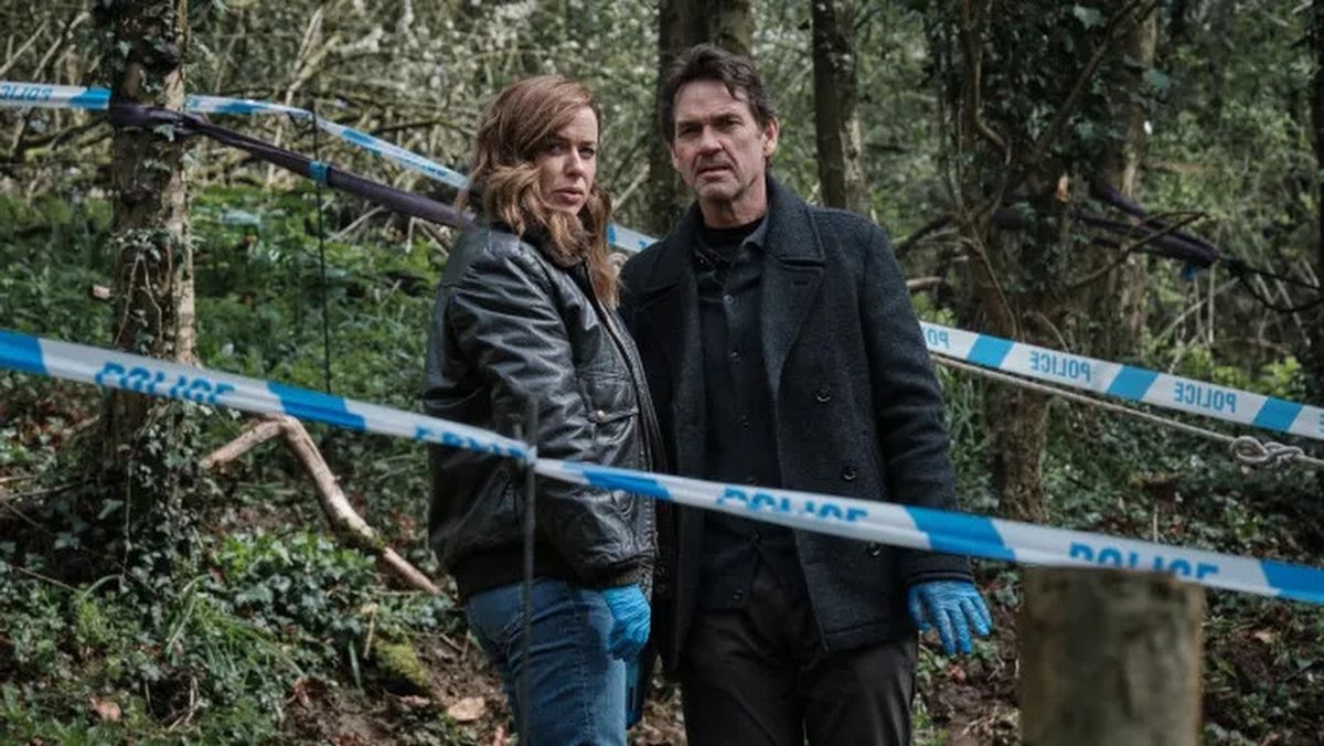 DCI Jeanette Kilburn (Eve Myles) and DI Lou Stanley (Dougray Scott) stand in a woodland crime scene in "The Crow Girl"
