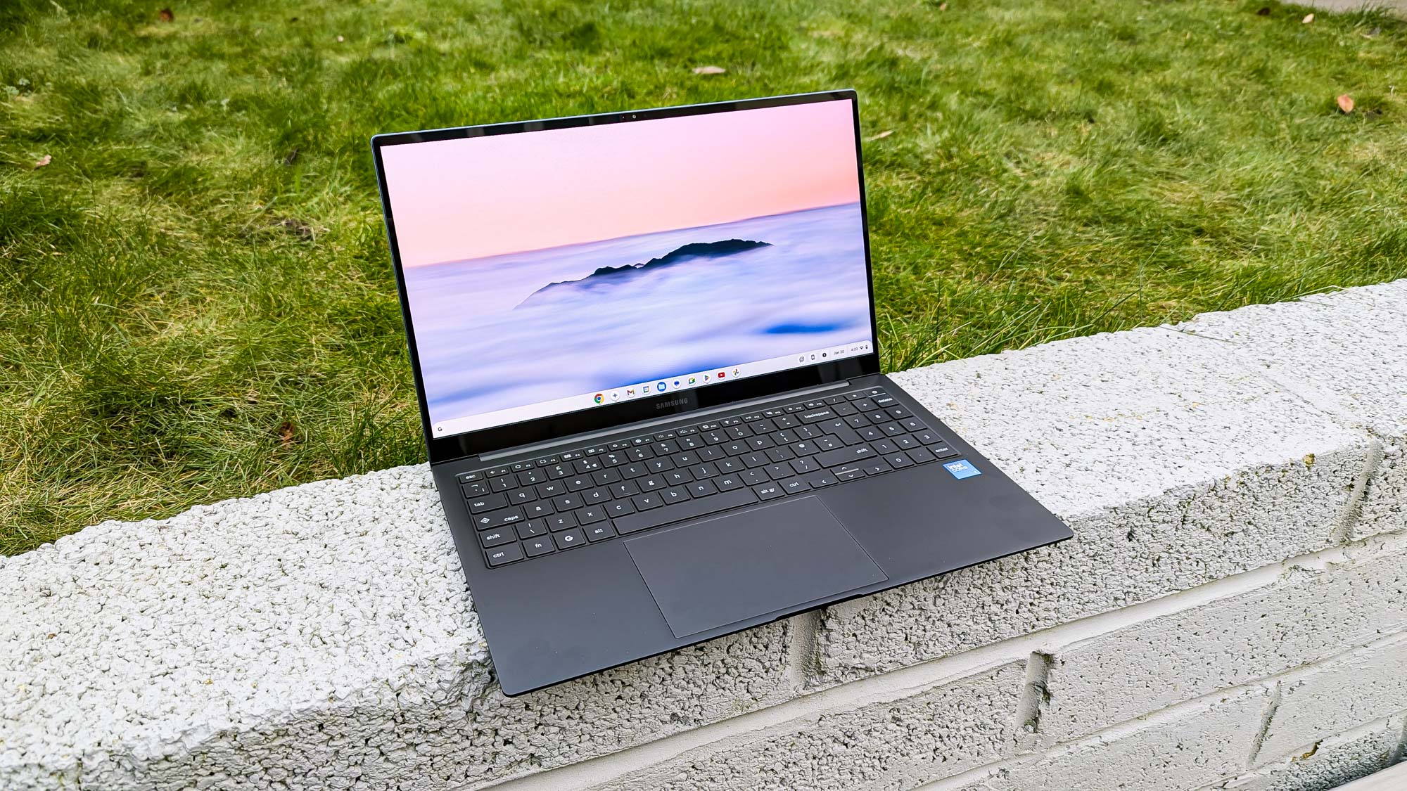 Samsung Galaxy Chromebook Plus ממוקם על הקיר עם רקע דשא