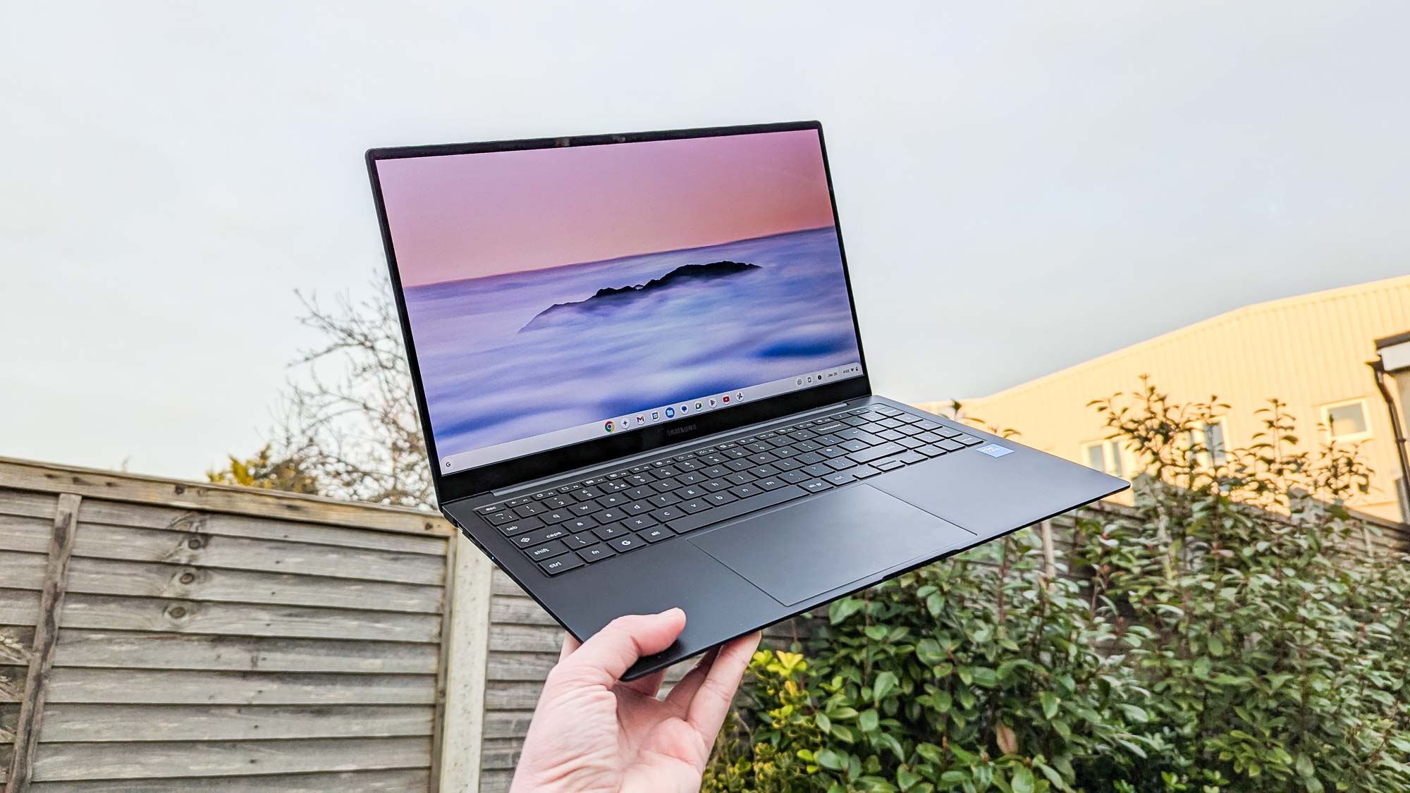 Samsung Galaxy Chromebook Plus מוחזק ביד ומחזיק עד השמיים