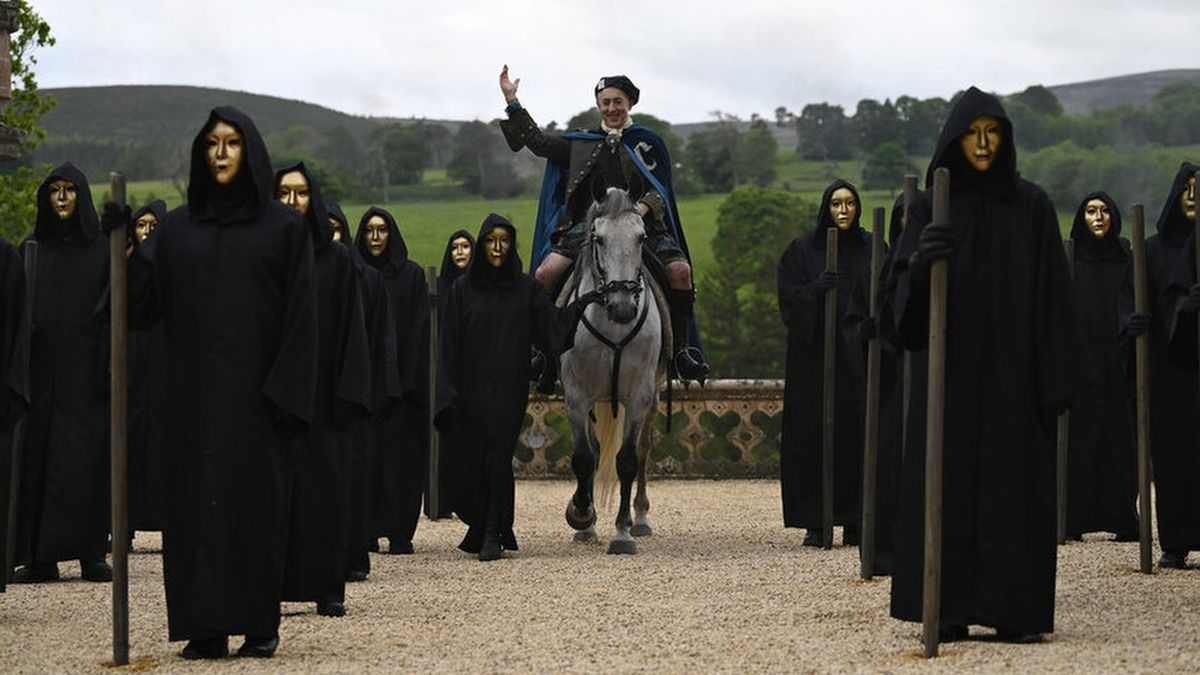 Host Alan Cumming, surrounded by masked, hooded figures, arrives at Traitors Castle on horseback