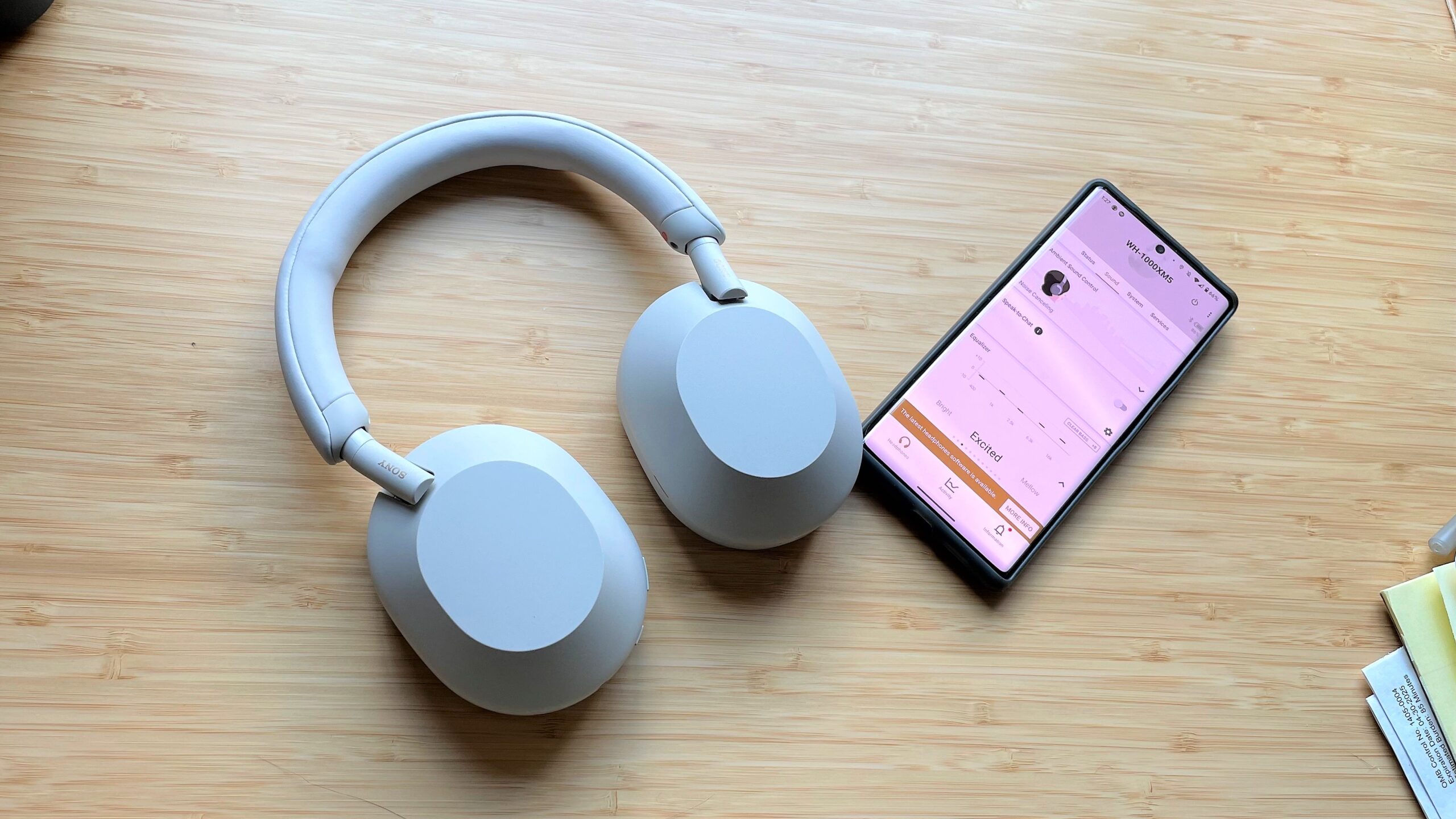 Sony WH-1000XM5 with iPhone on a wooden desktop